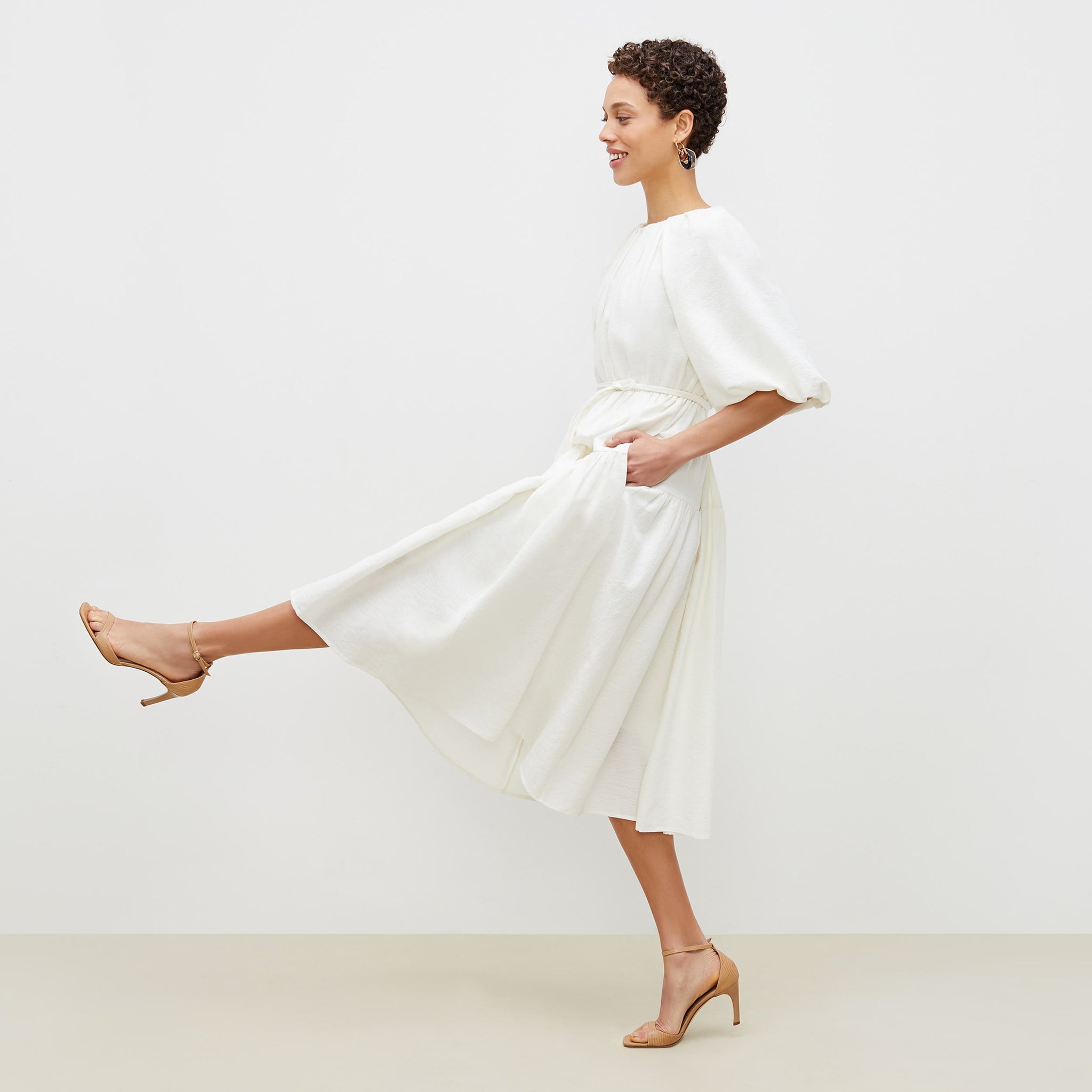 Side image of a woman standing wearing the medina dress in textured voile in ivory