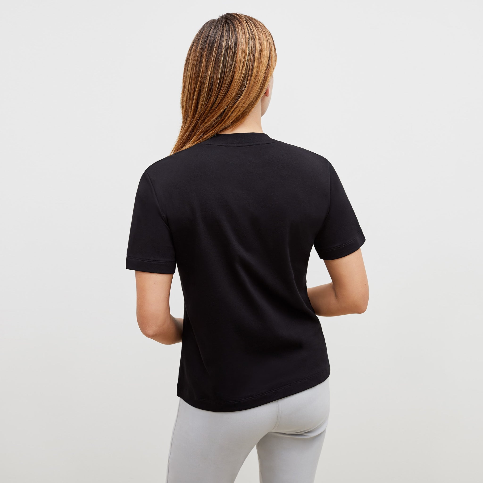 Back image of a woman standing wearing the leslie top in compact cotton in black