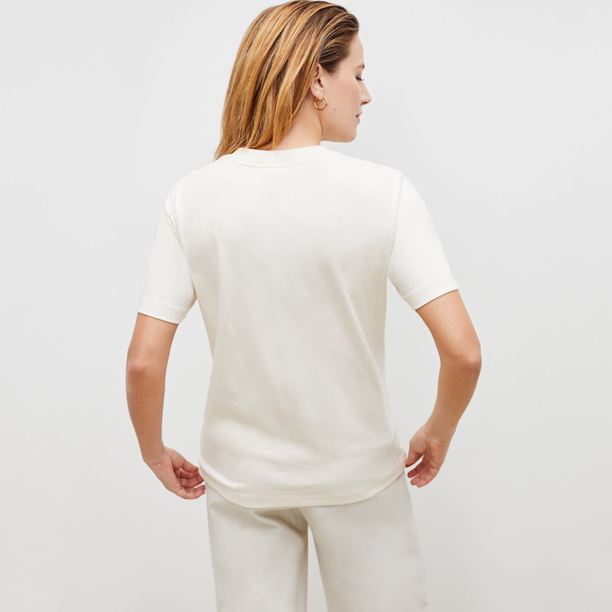 Back image of a woman standing wearing the leslie top in compact cotton in ivory