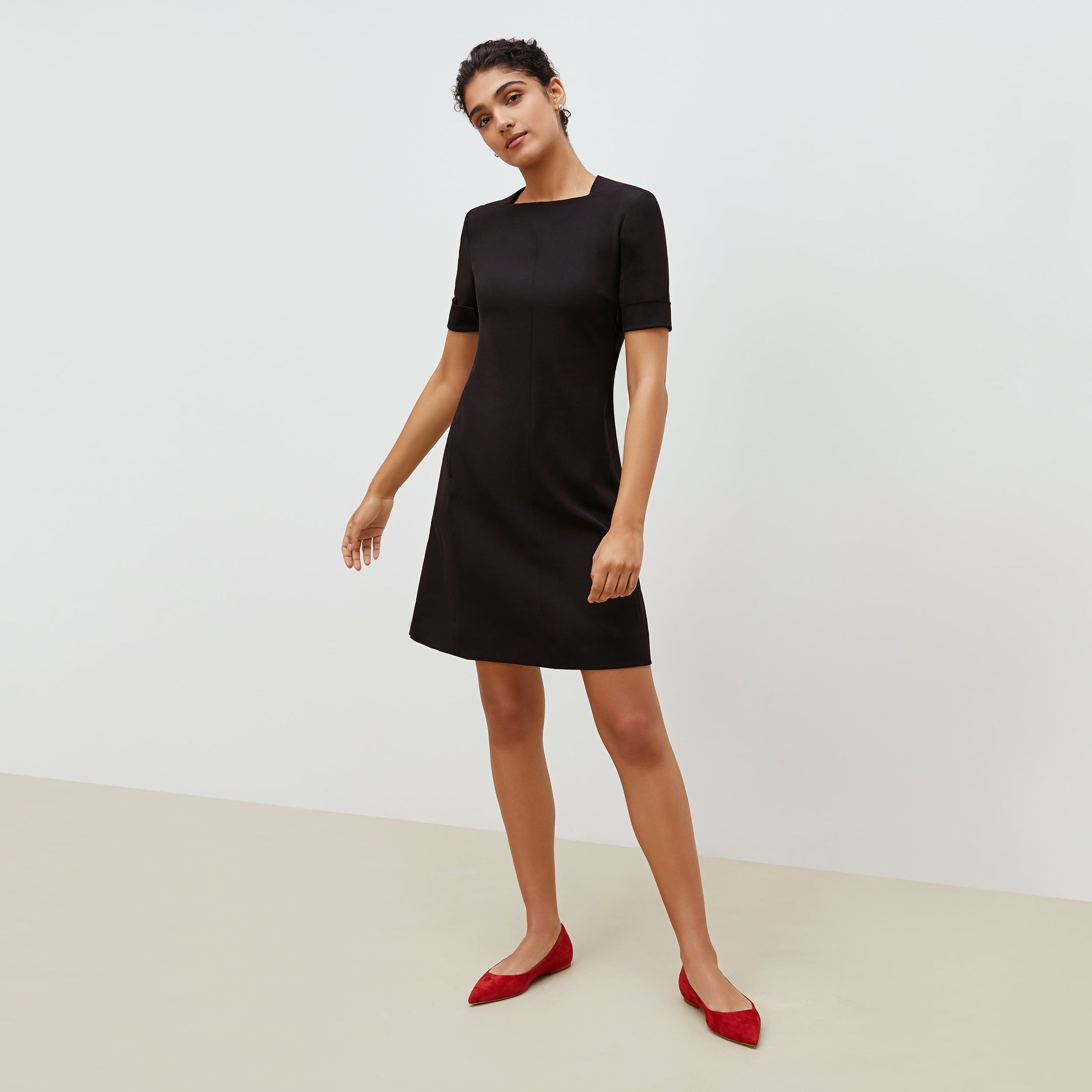 Front image of a woman standing wearing the emily dress in black