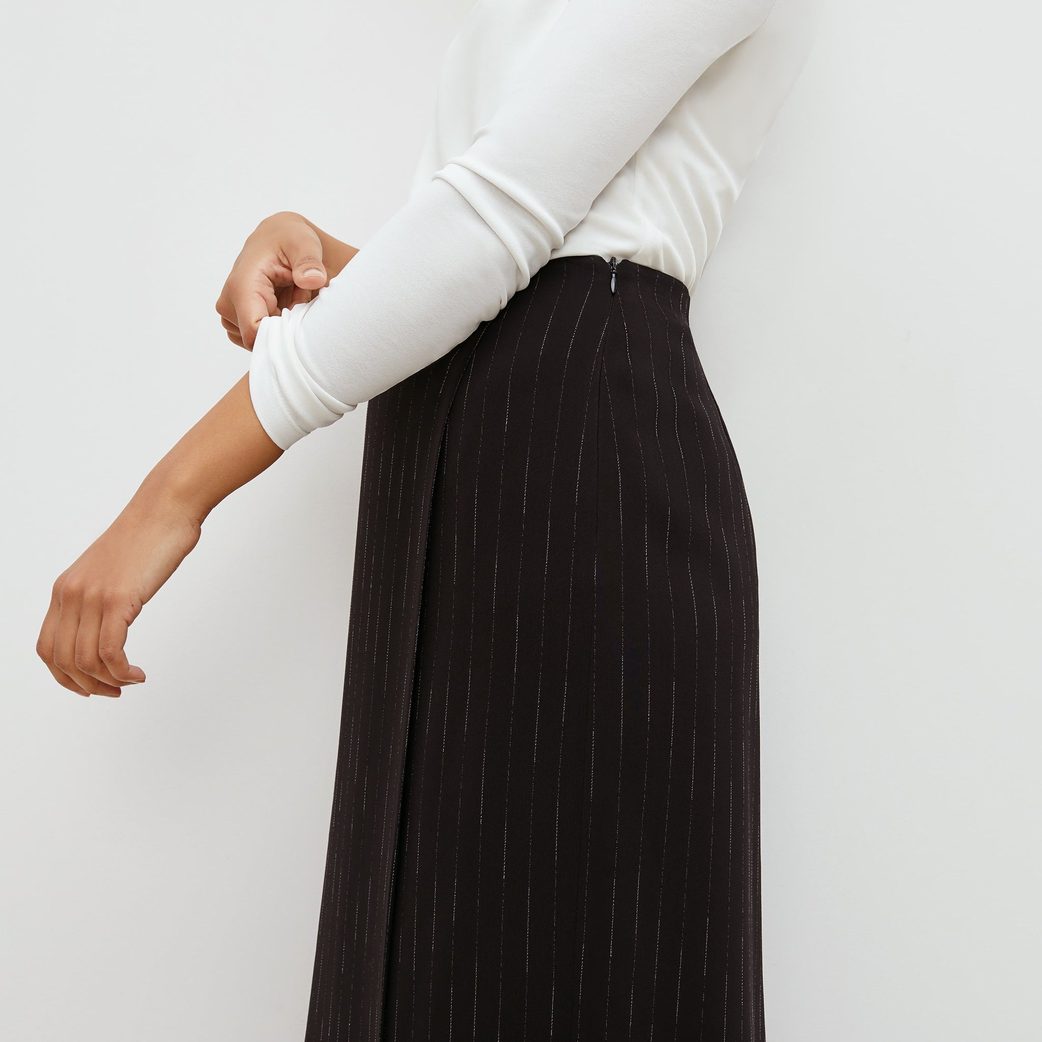Side image of a woman standing wearing the Logan Skirt in black