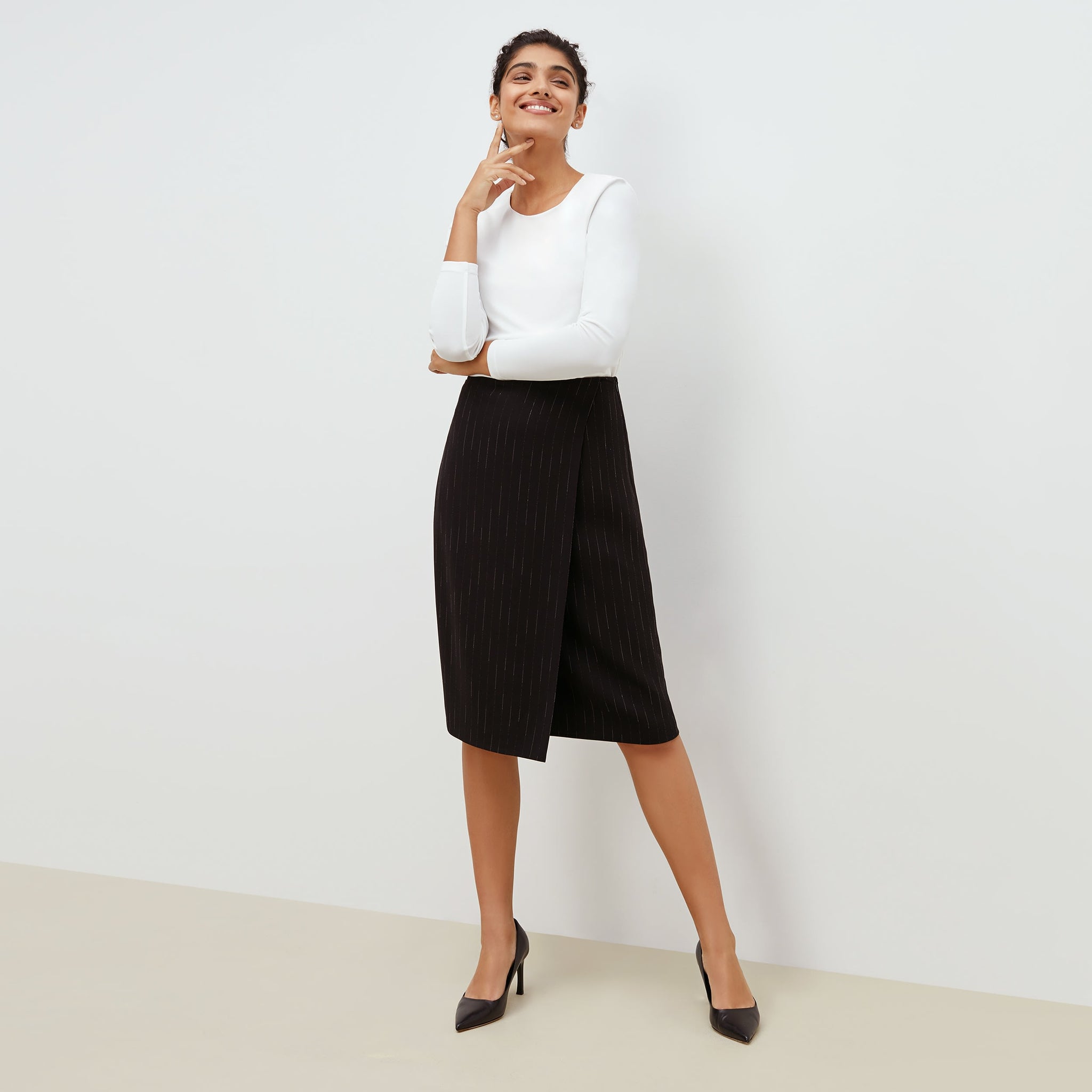 Front image of a woman standing wearing the Logan Skirt in black