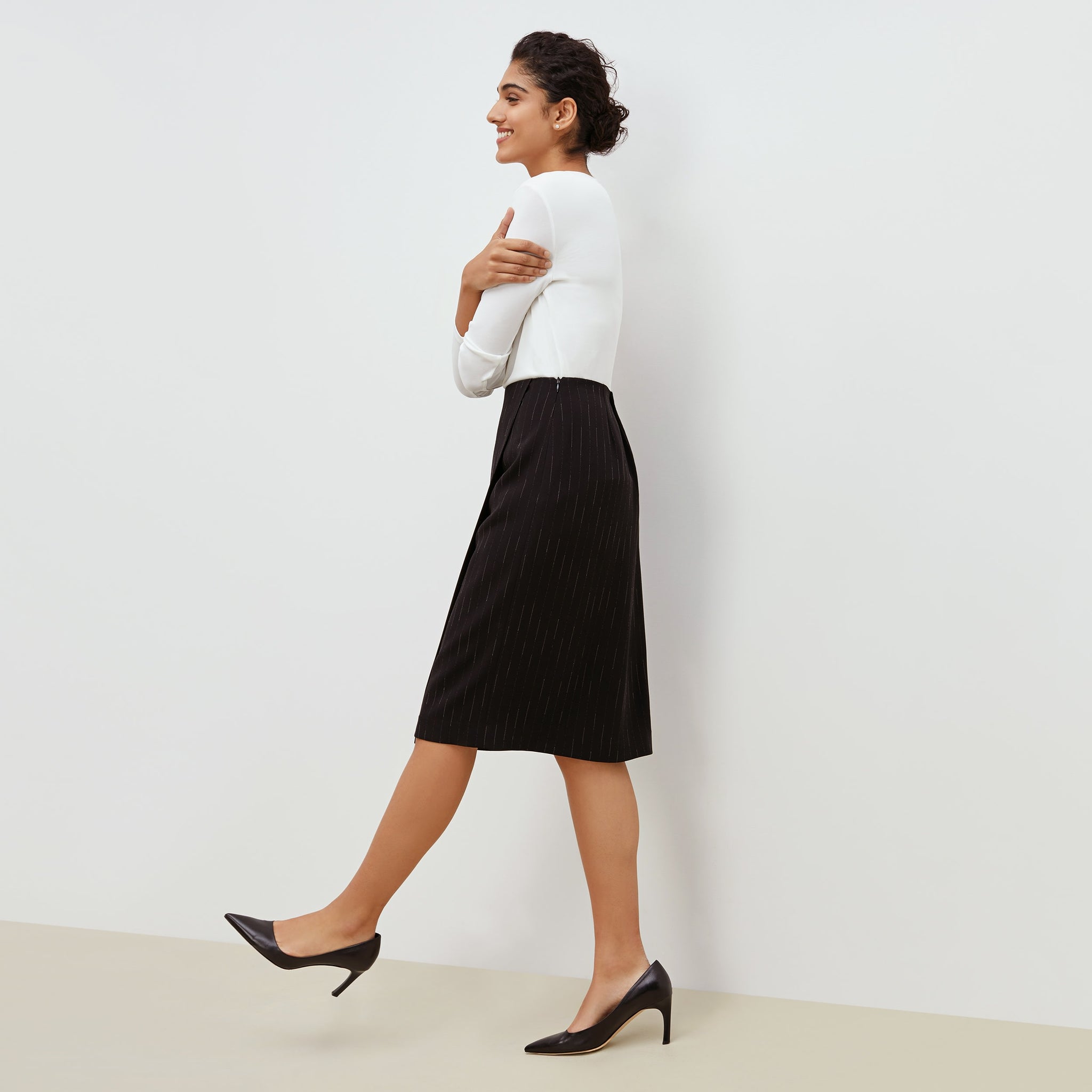 Side image of a woman standing wearing the Logan Skirt in black