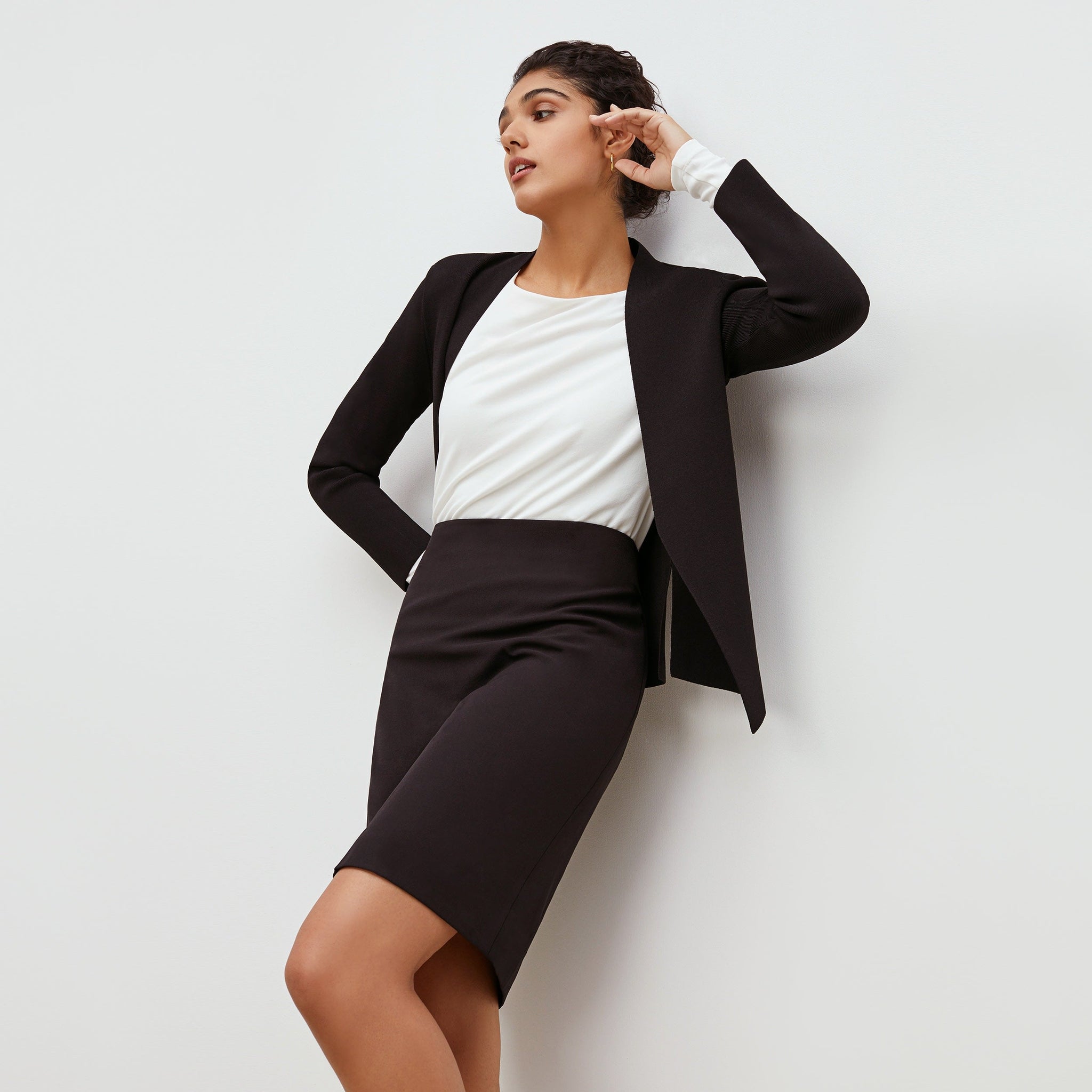 Front image of a woman standing wearing the Noho skirt in black.