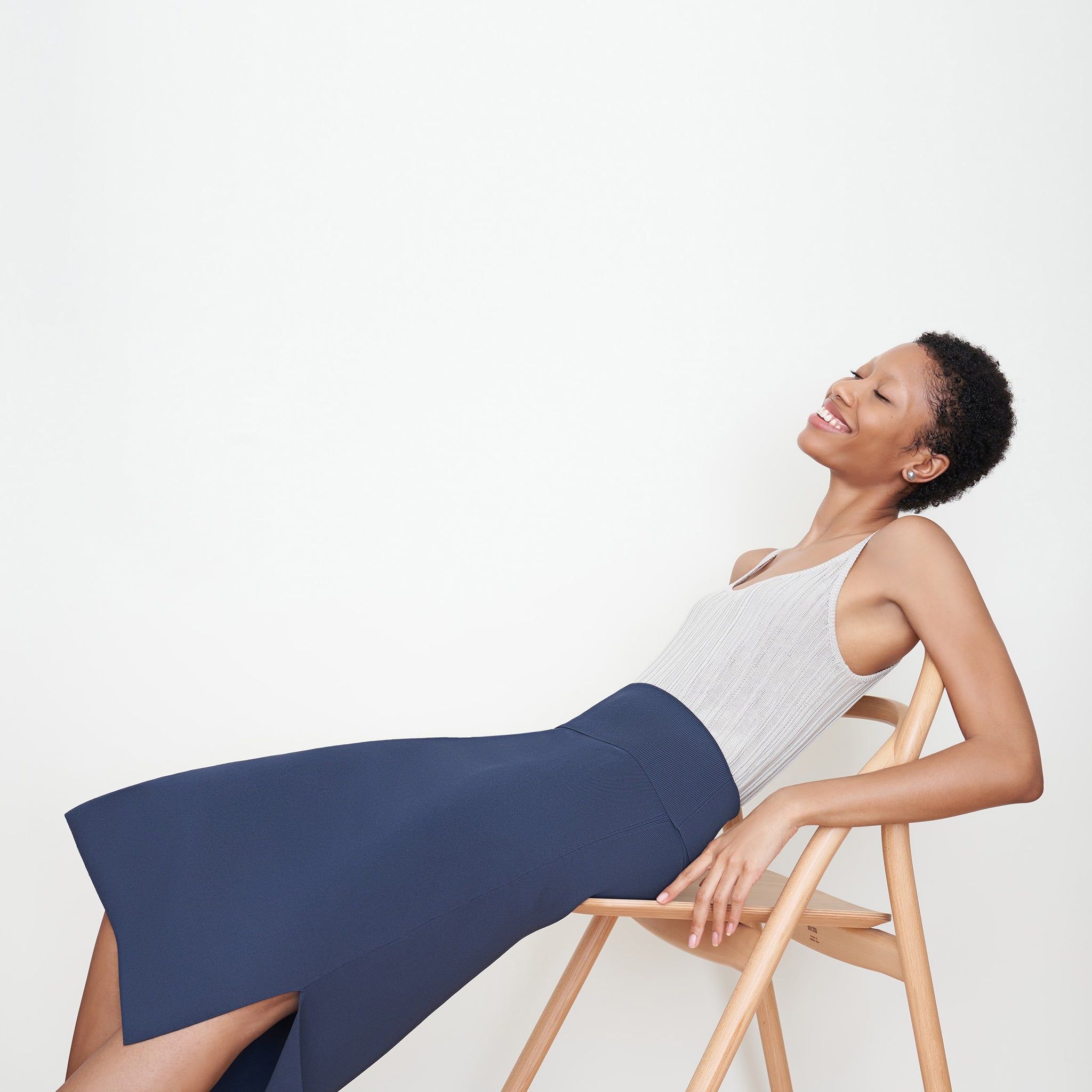 Side image of a woman sitting wearing the Harlem skirt in jardigan knit in Baltic Blue