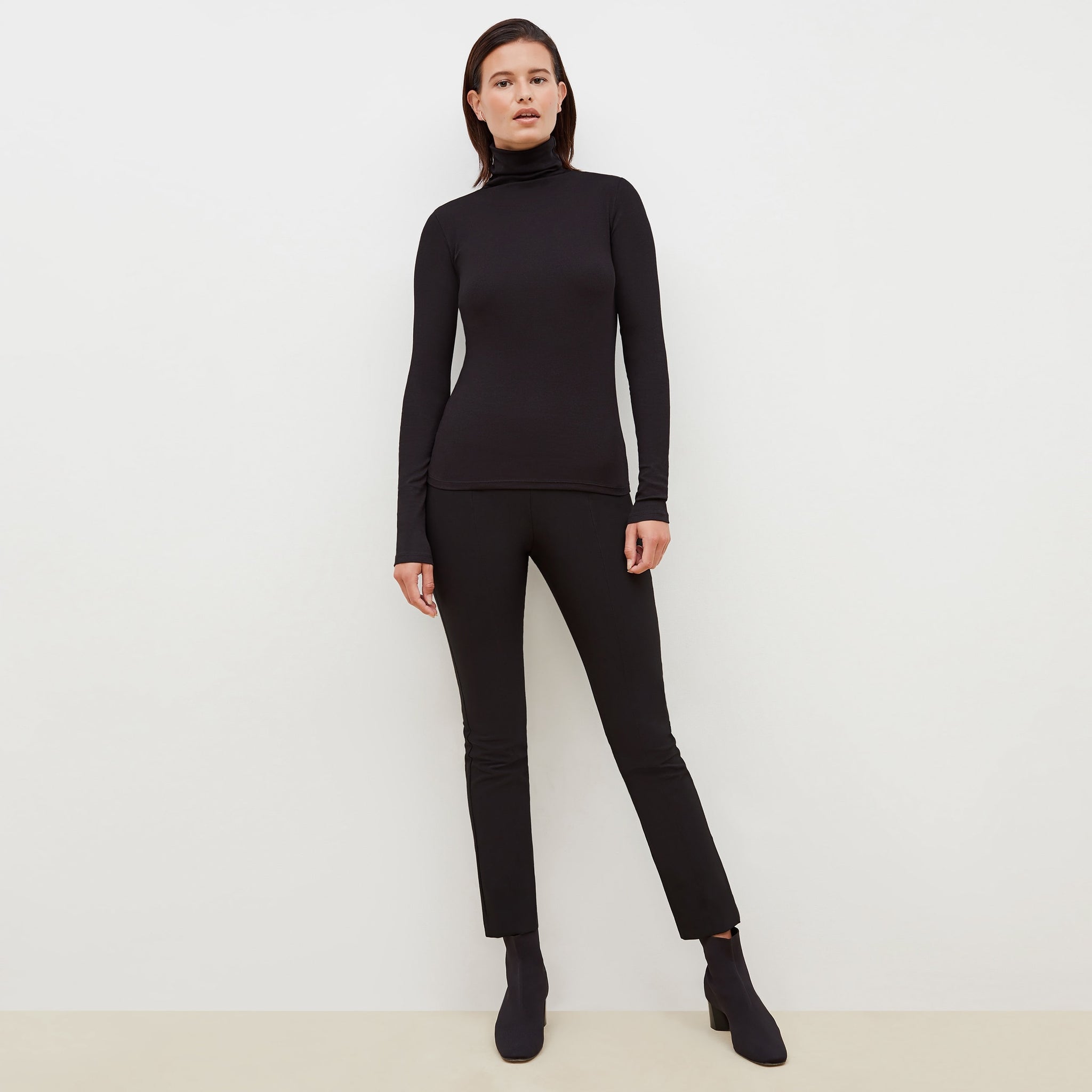 Front image of a woman standing wearing the axam top in black