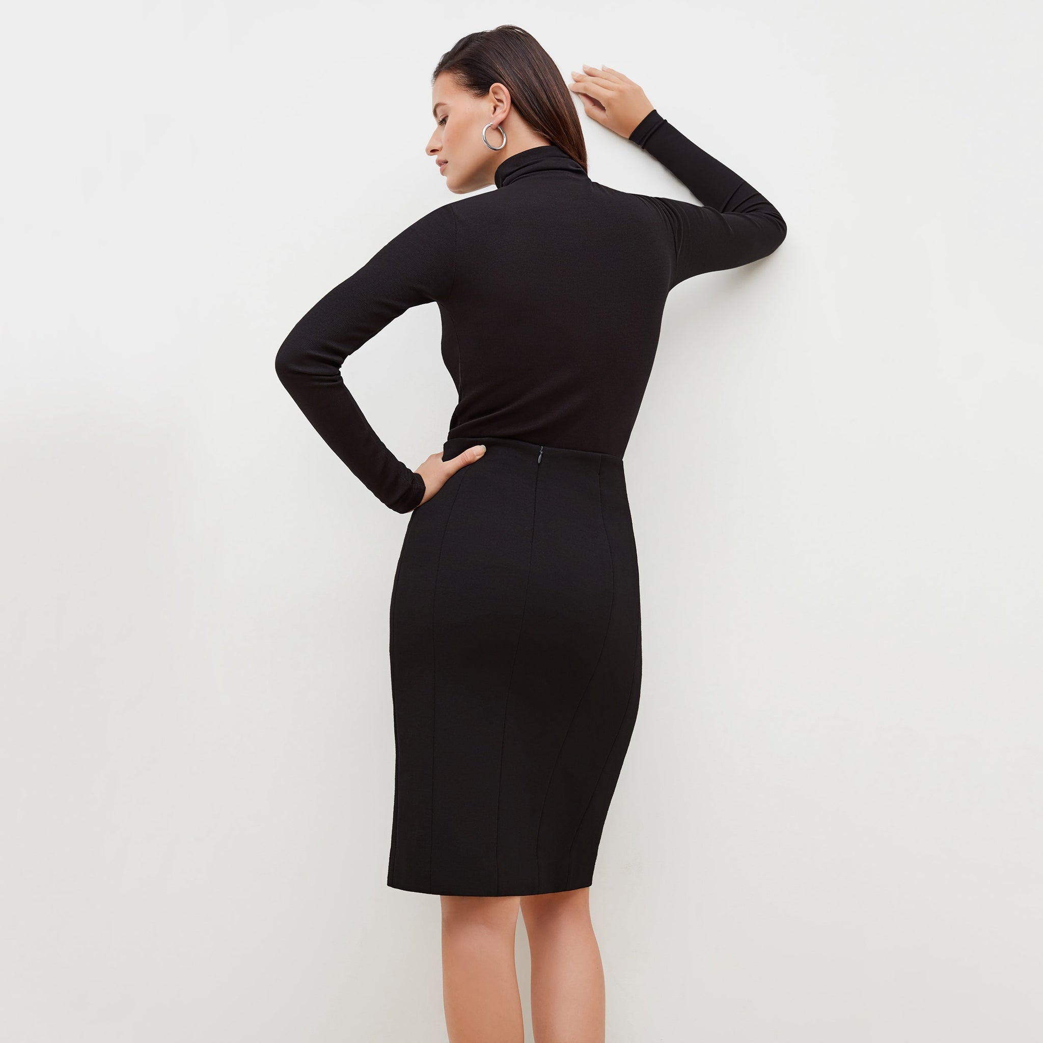 Back image of a woman standing wearing the axam top in black