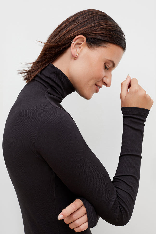 Front image of a woman standing wearing the axam top in black 