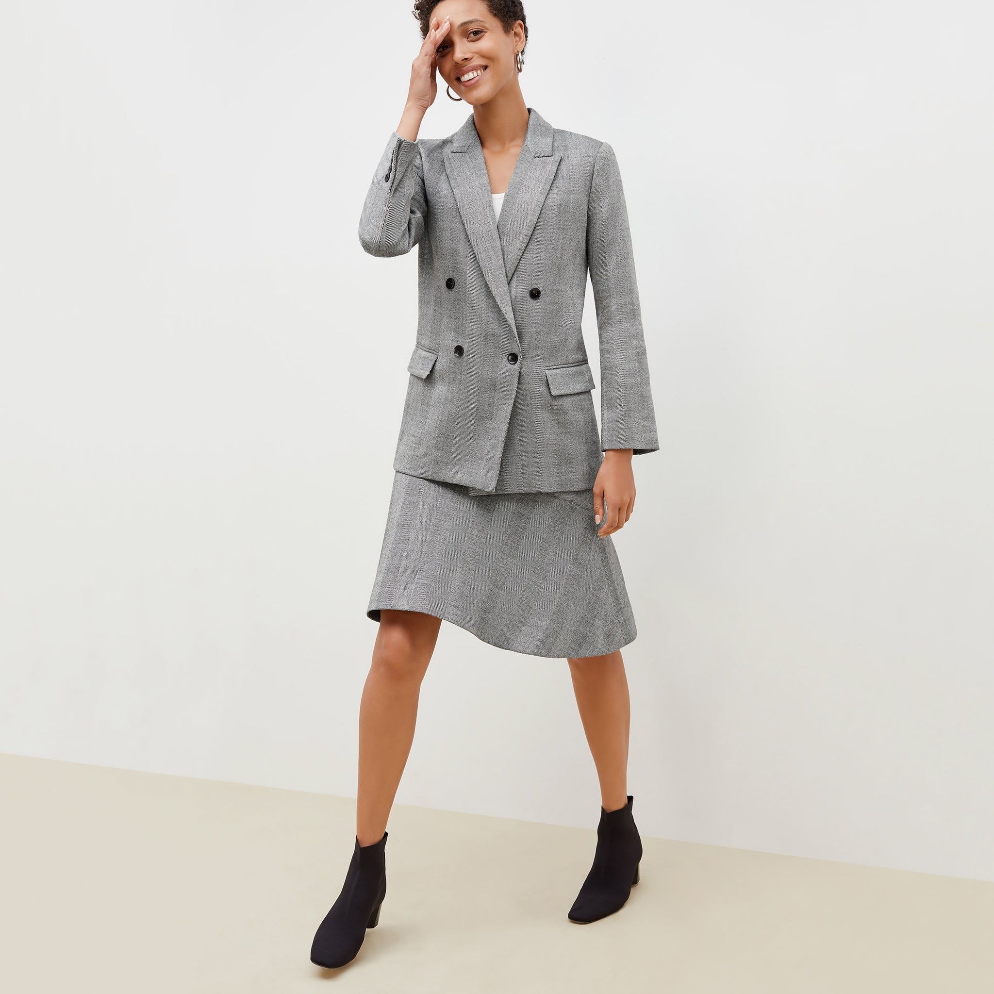 Front image of a woman standing wearing the o'hara blazer in wool herringbone in ivory and black 