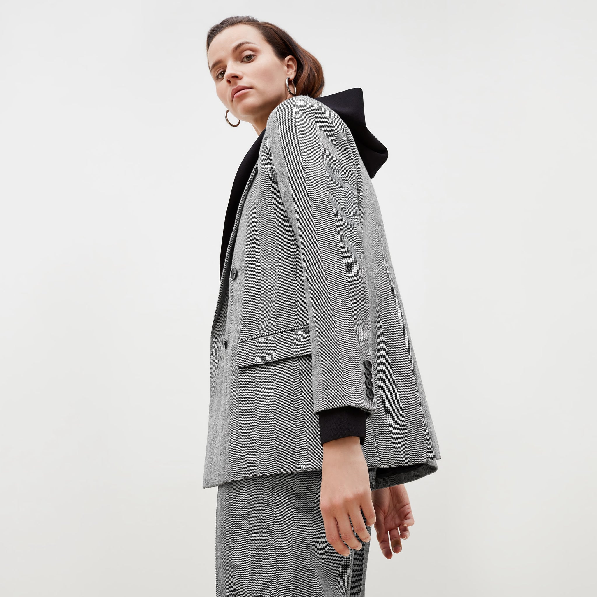 Side image of a woman standing wearing the o'hara blazer in wool herringbone in ivory and black