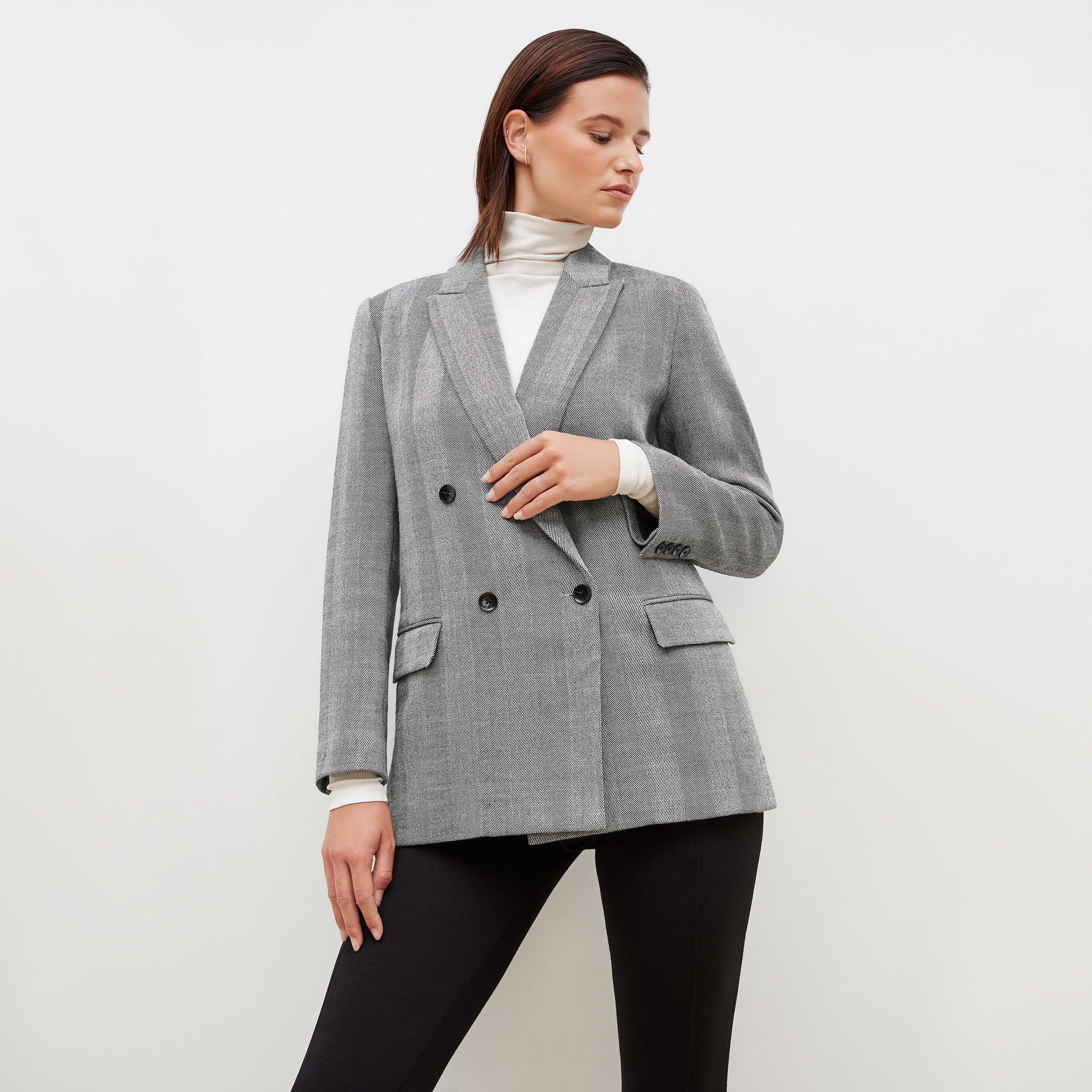 Front image of a woman standing wearing the o'hara blazer in wool herringbone in ivory and black
