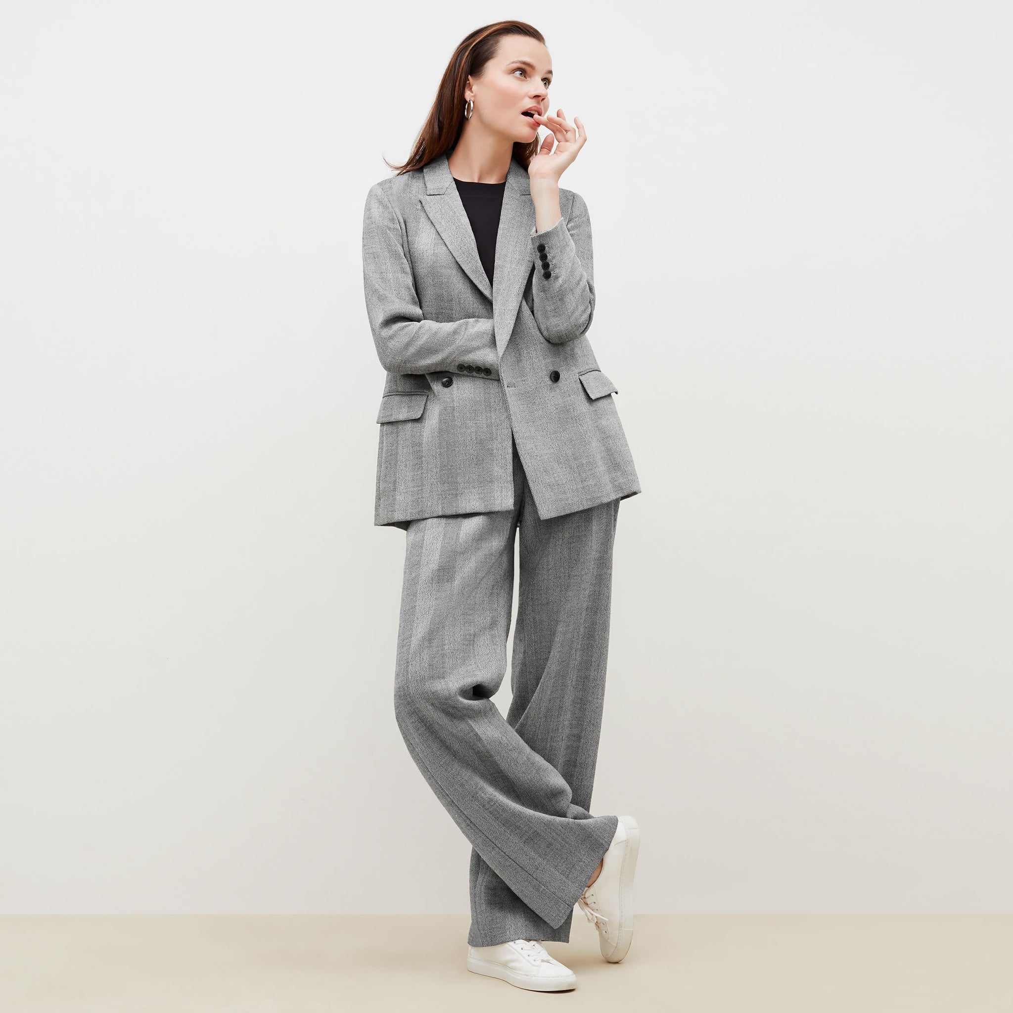 Front image of a woman standing wearing the o'hara blazer in wool herringbone in ivory and black