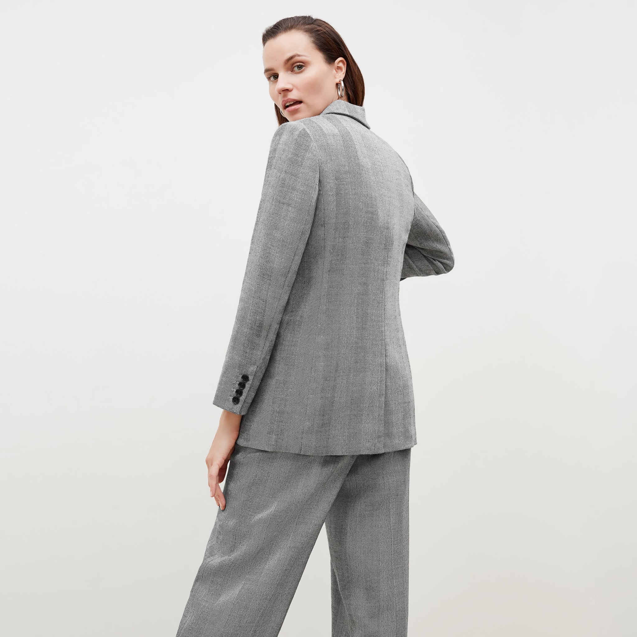 Back image of a woman standing wearing the o'hara blazer in wool herringbone in ivory and black