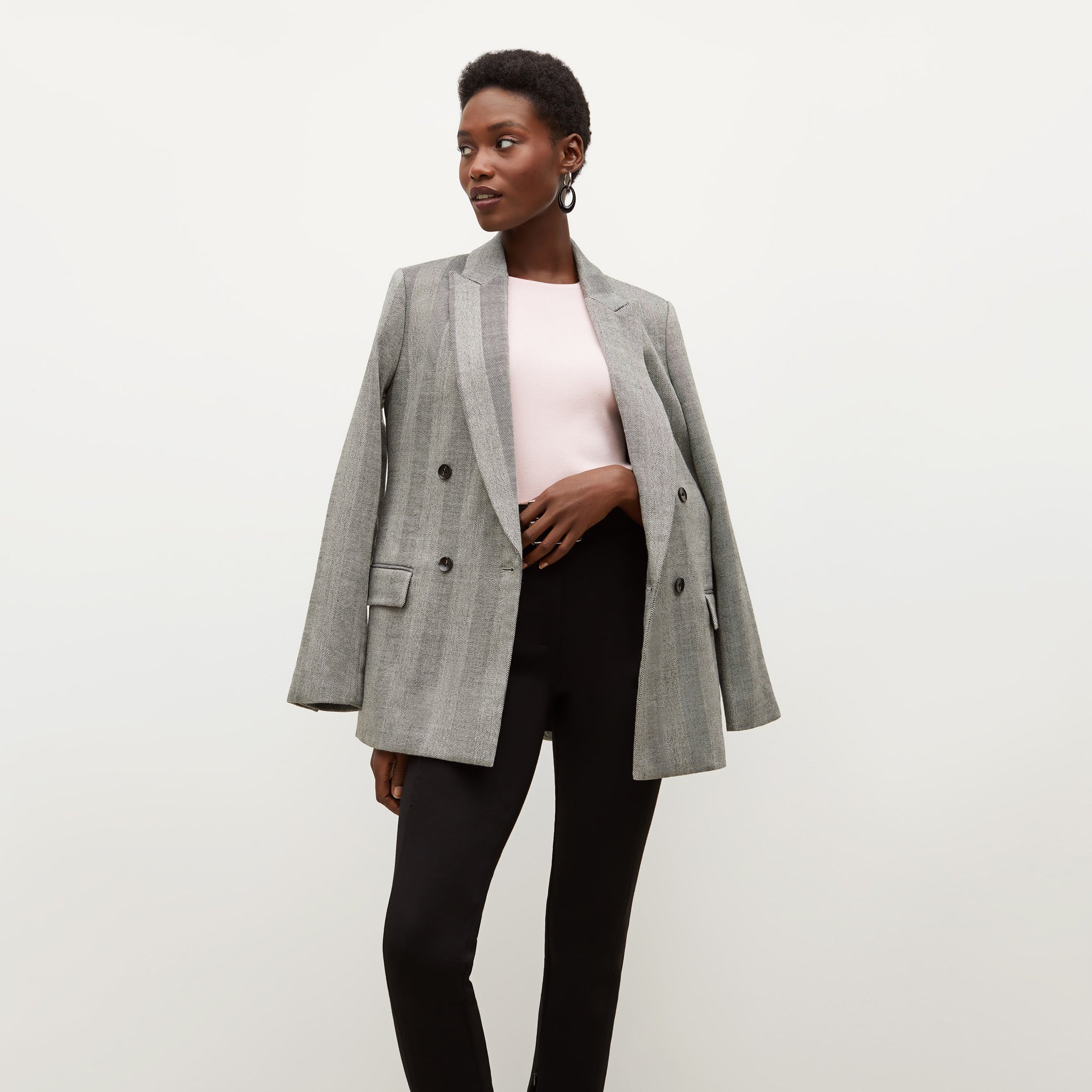 Front image of a woman standing wearing the o'hara blazer in wool herringbone in ivory and black