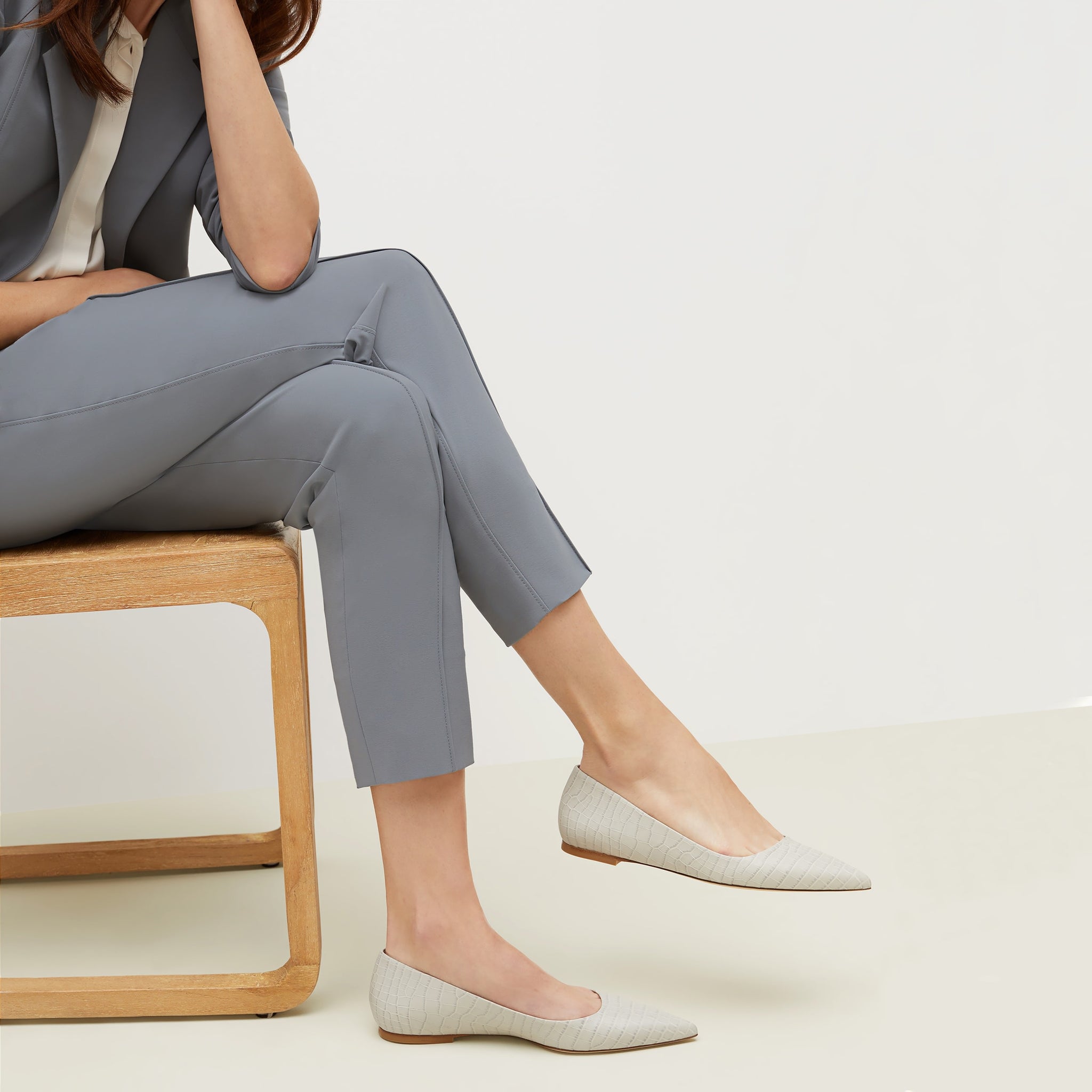 Side image of a woman sitting wearing the Rowan Flat—Embossed Croc in Gray