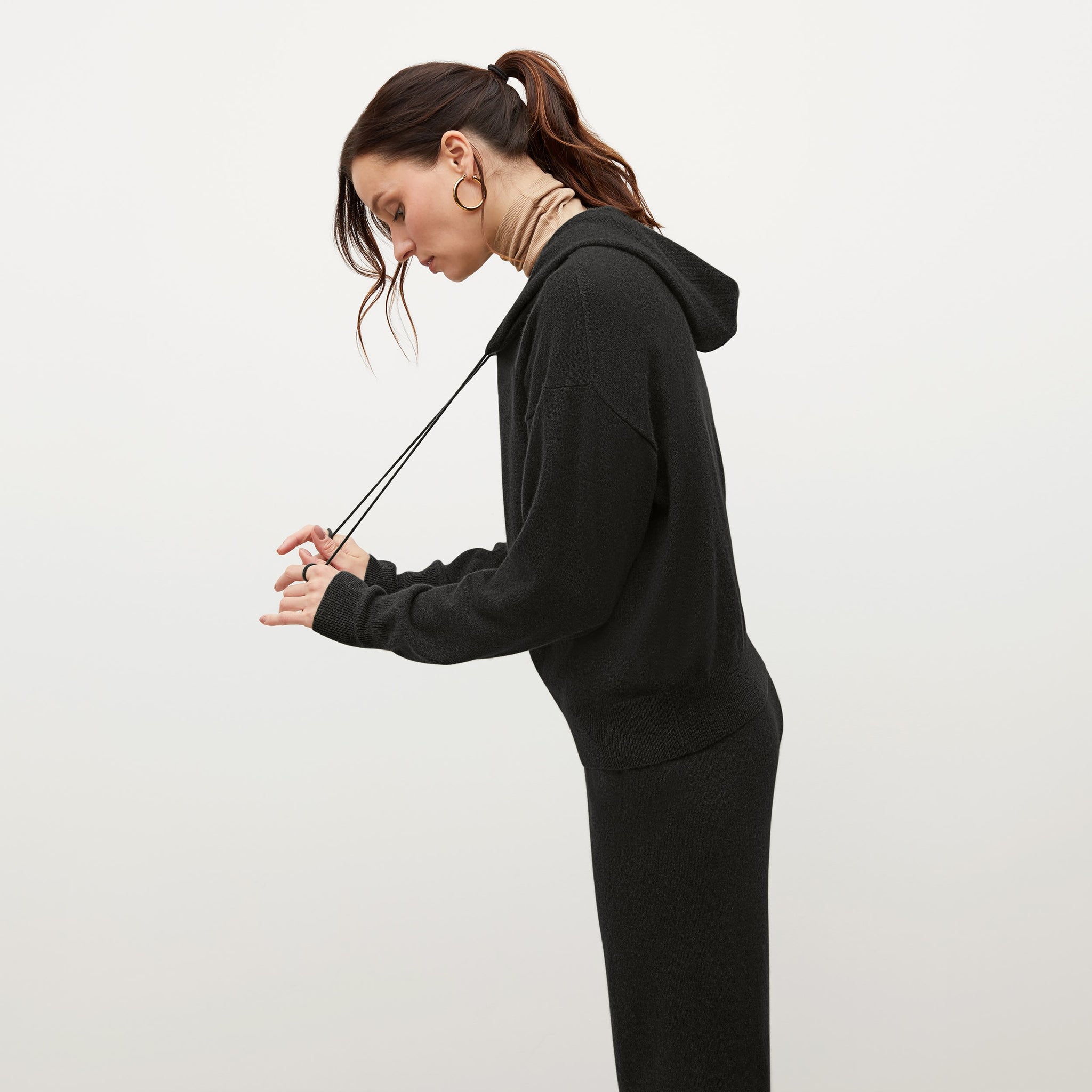 Side image of a woman standing wearing the Judith Hoodie—Cashmere in Black