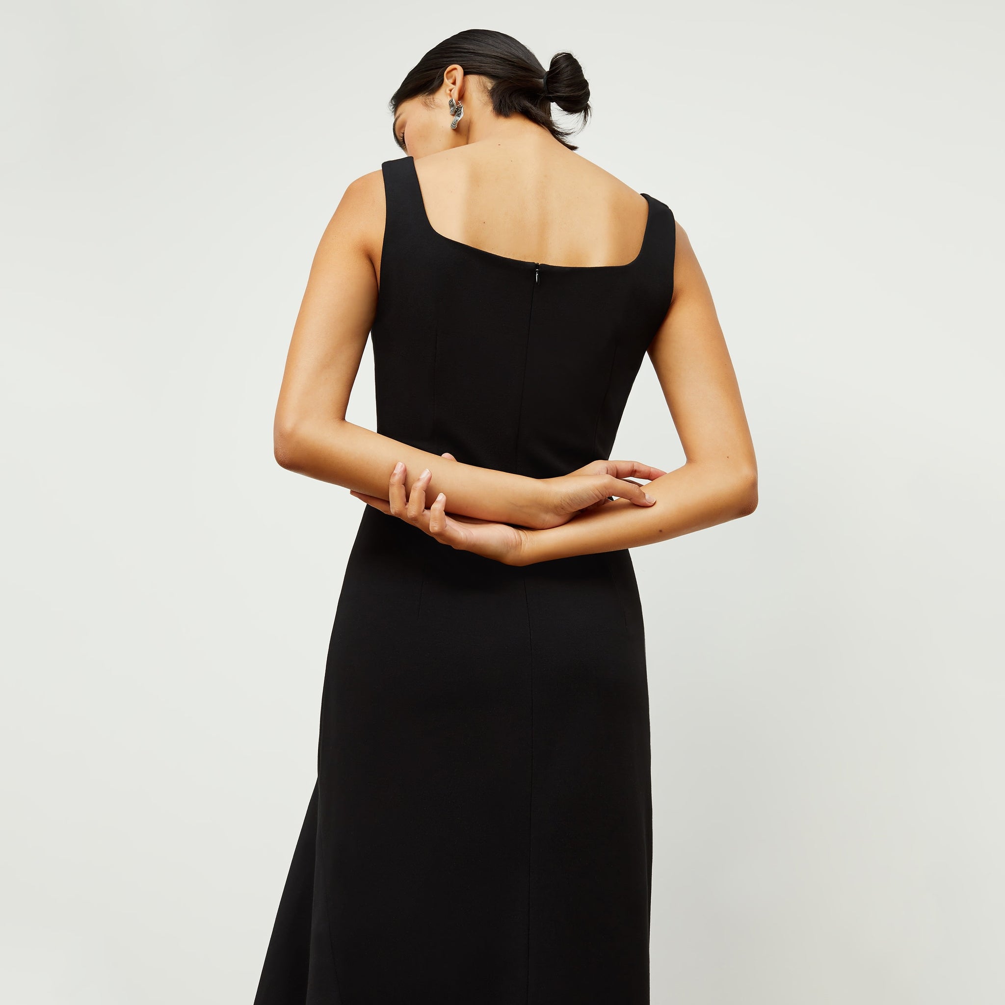Back image of a woman standing wearing the james dress in black