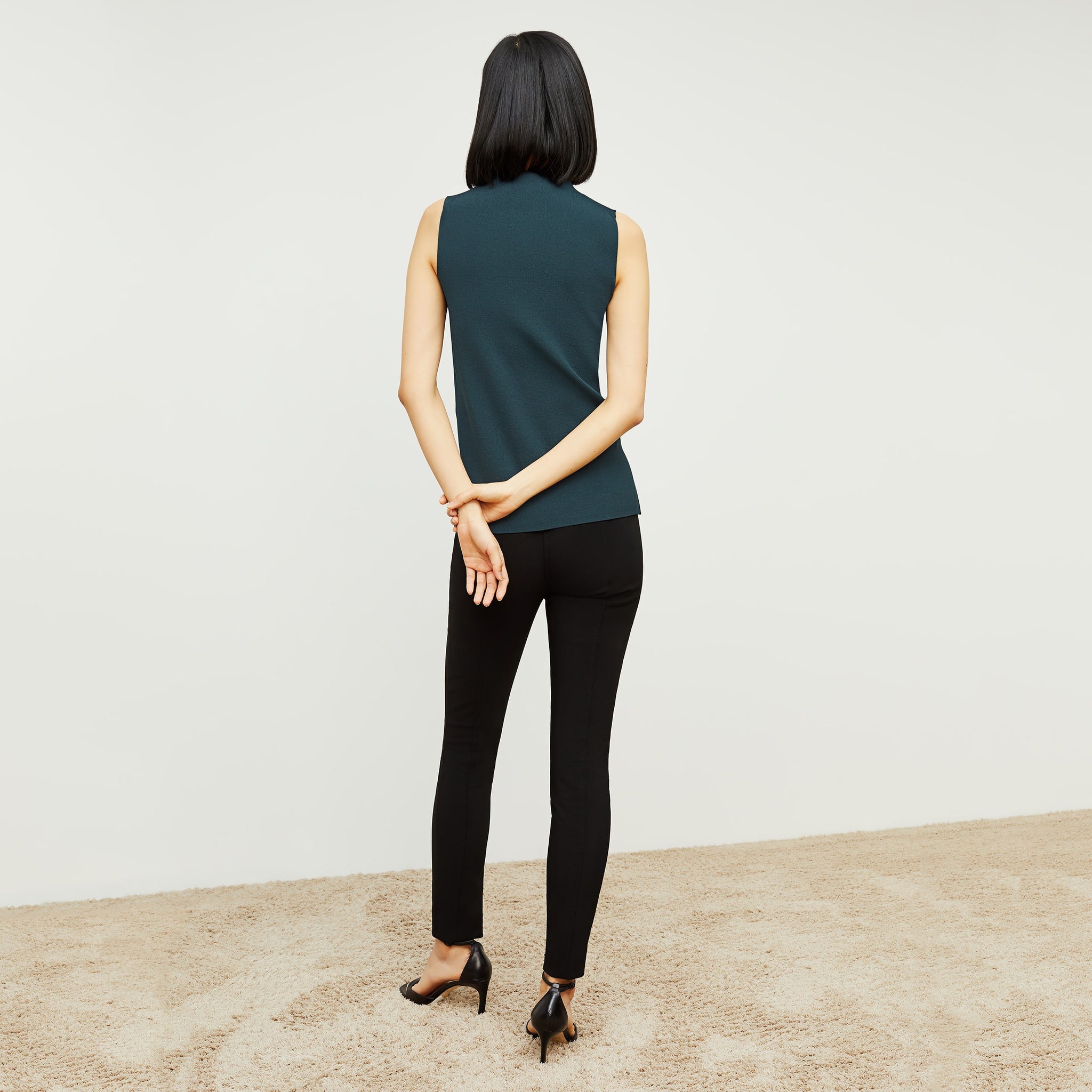 Back image of a woman standing wearing the curie pant in black