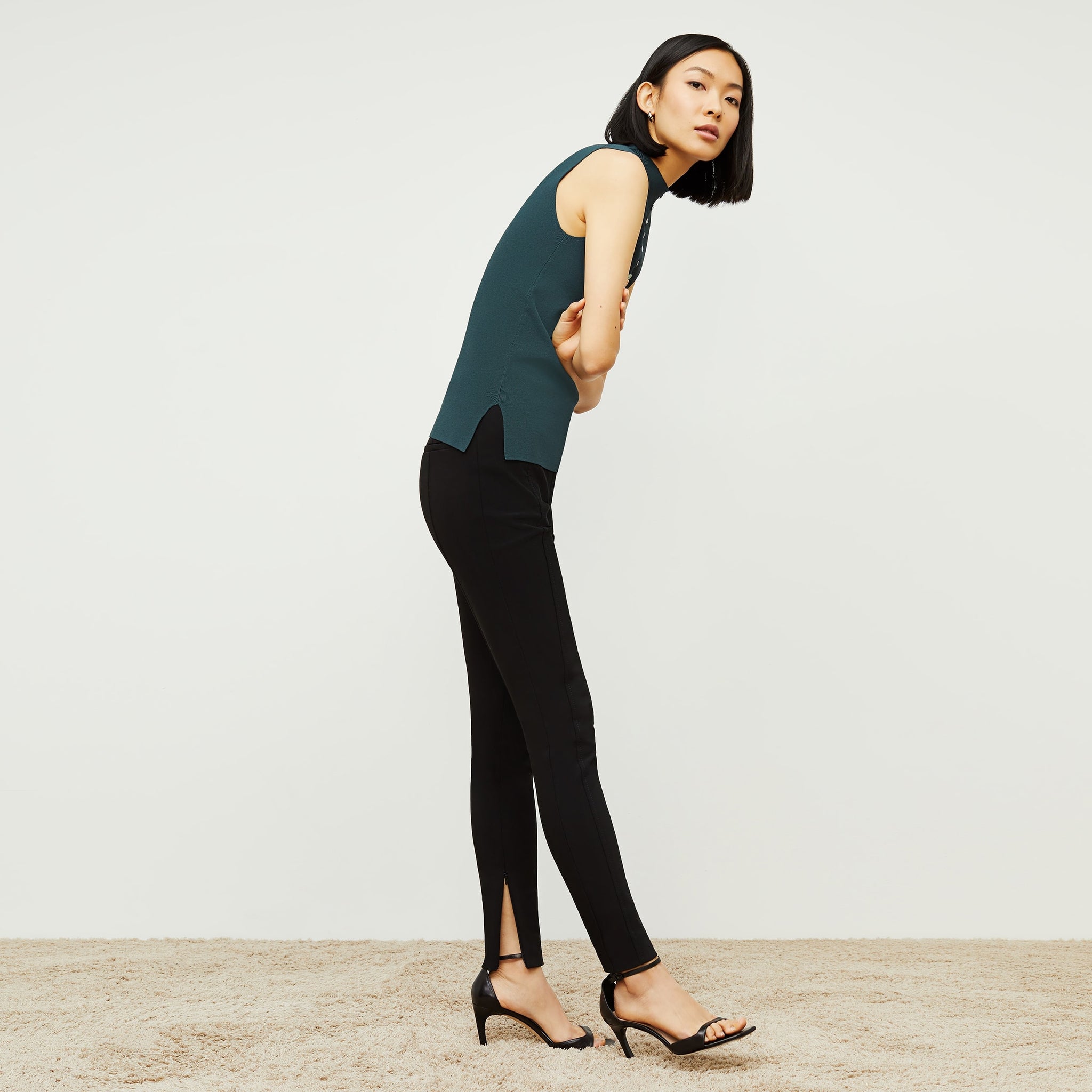 Side image of a woman standing wearing the curie pant in black