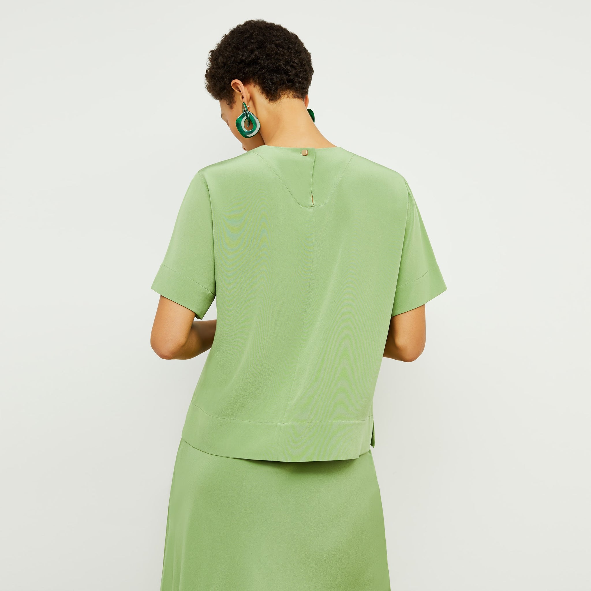 Back image of a woman standing wearing the Annika Tee—Washable Silk in Cactus