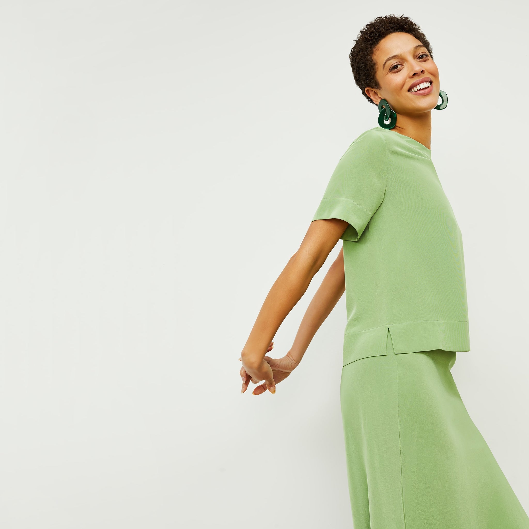 Side image of a woman standing wearing the Annika Tee—Washable Silk in Cactus