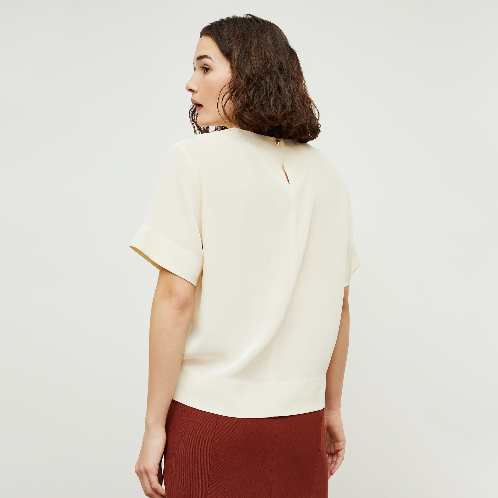 Back image of a woman standing wearing the Annika Tee—Washable Silk in Pearl