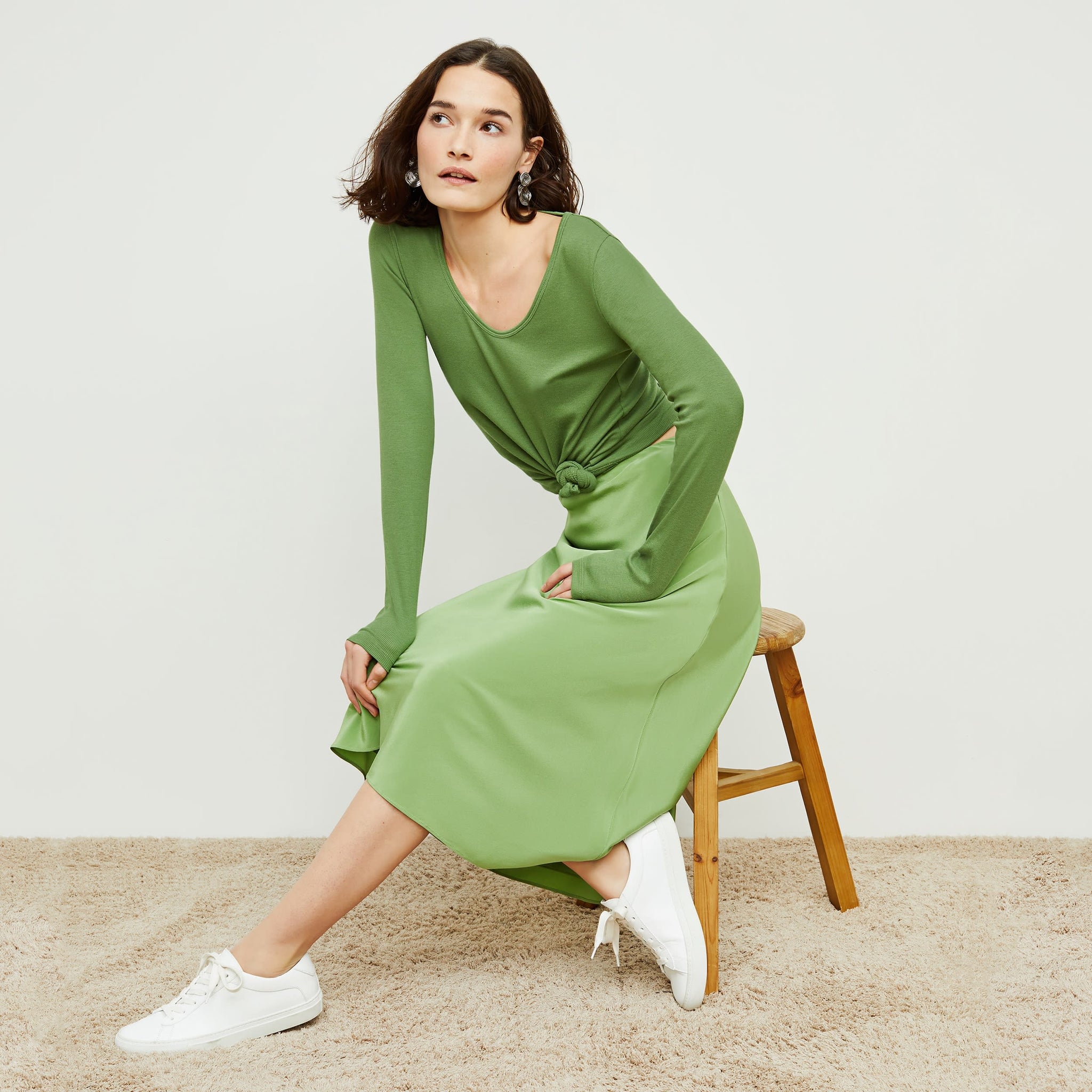 Side image of a woman sitting wearing the Orchard Skirt—Washable Silk in Cactus