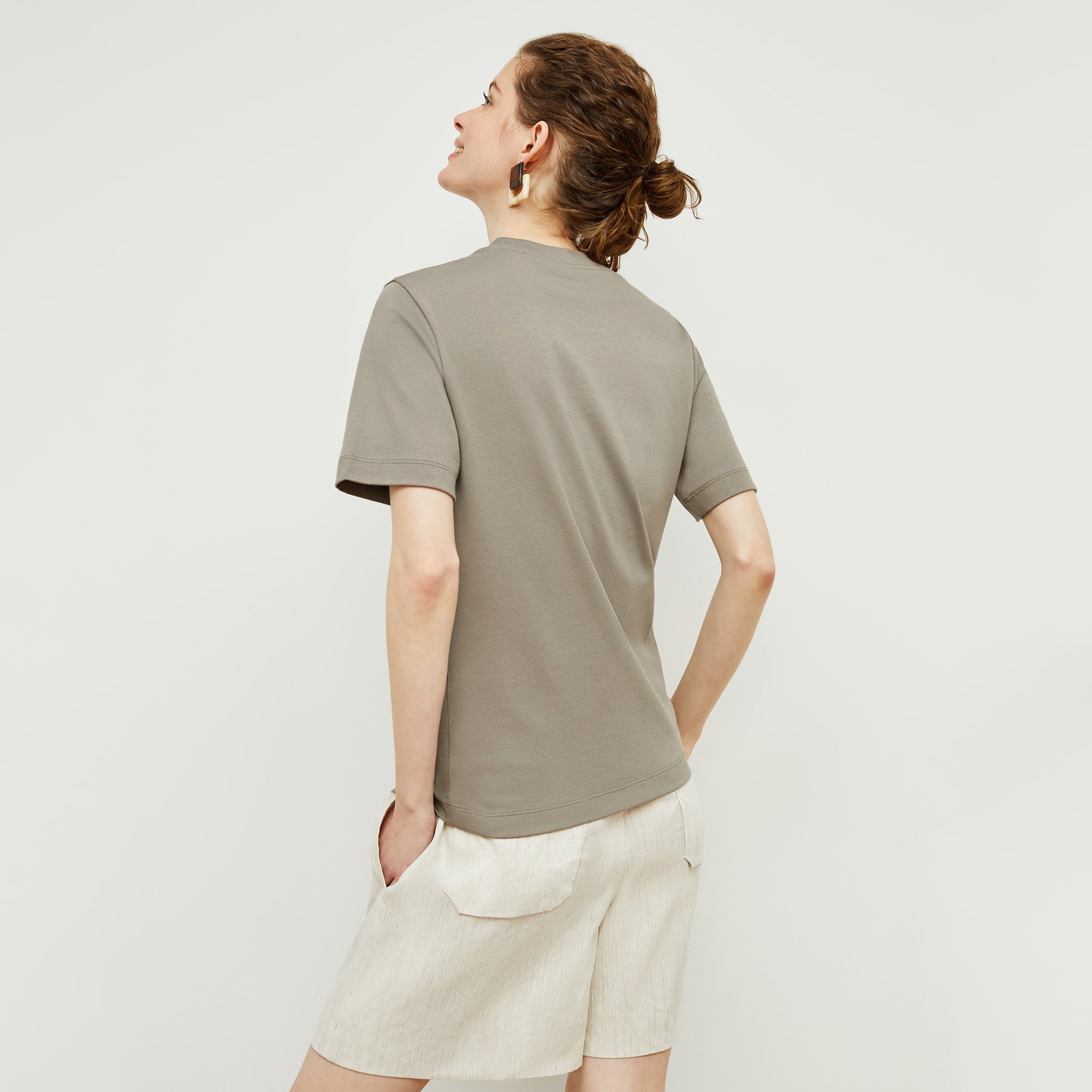 Back image of a woman standing wearing the Leslie T-Shirt—Compact Cotton in Pebble