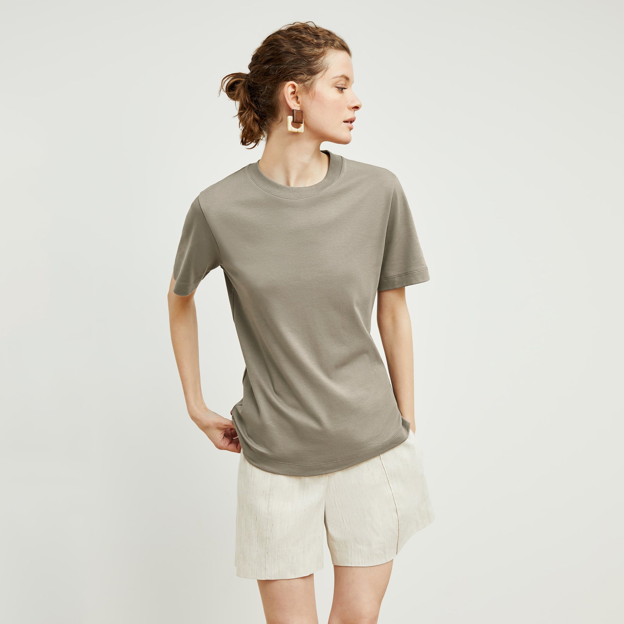 Front image of a woman standing wearing the Leslie T-Shirt—Compact Cotton in Pebble