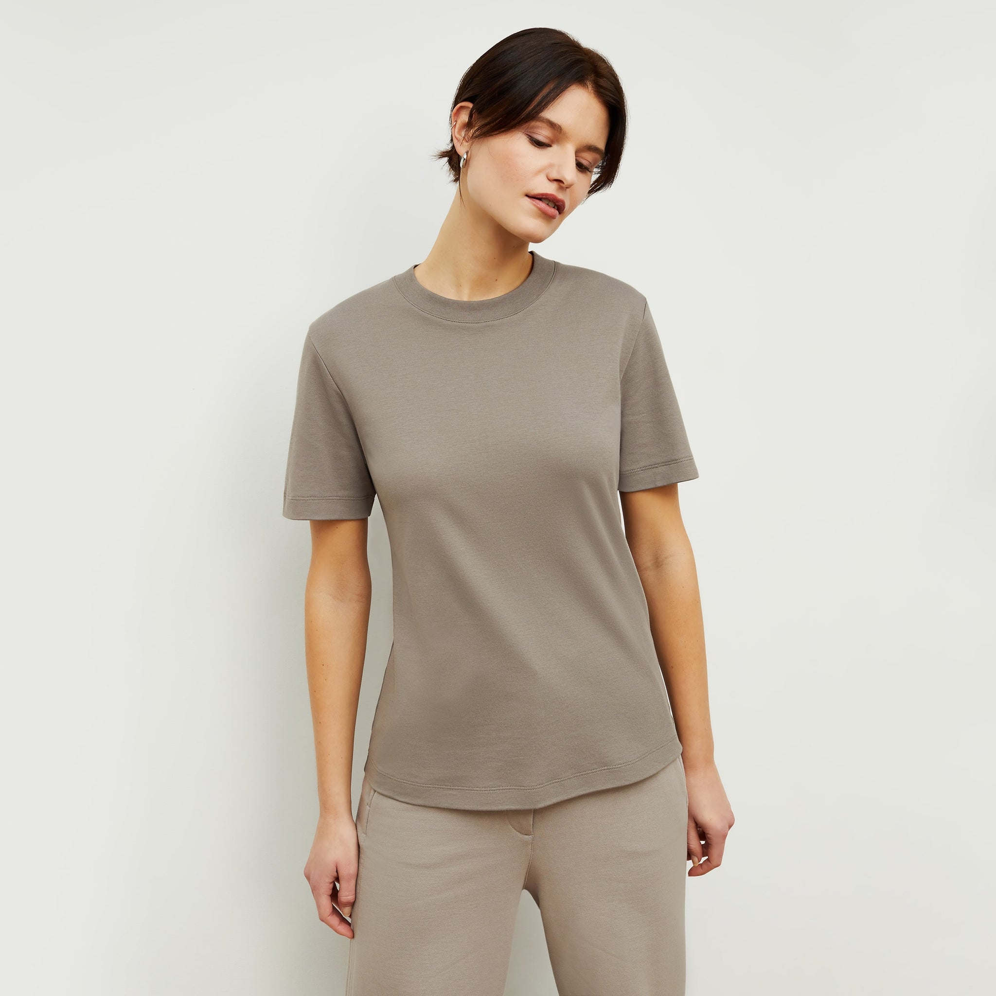 Front image of a woman standing wearing the Leslie T-Shirt—Compact Cotton in Pebble