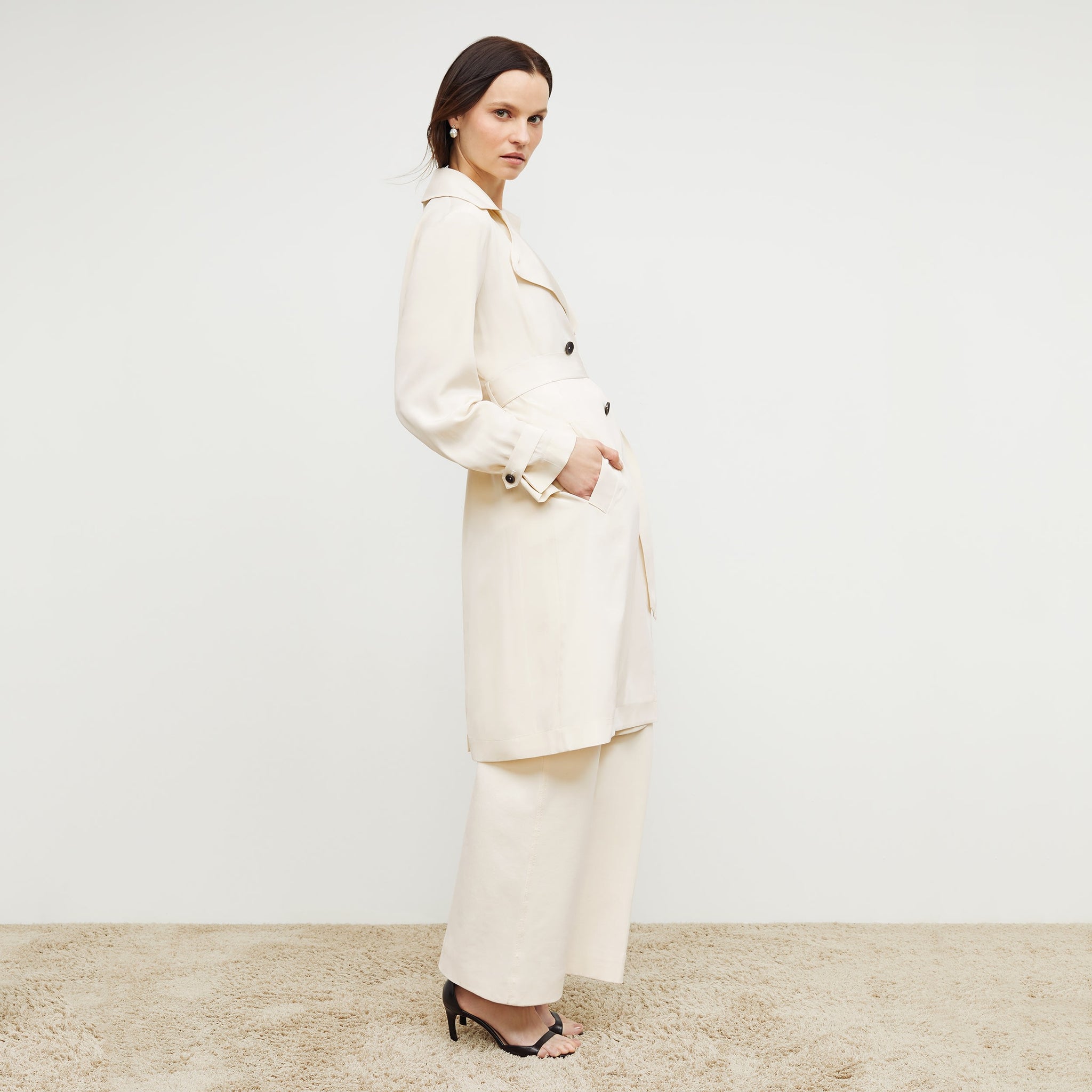 Side image of a woman standing wearing the Jensen Trench—SustainSilk in Pearl