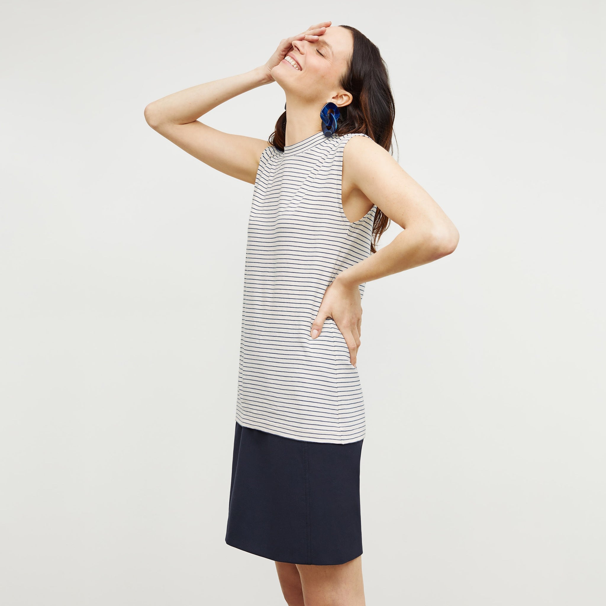 Side image of a woman standing wearing the Alina T-Shirt—Thin Striped Cotton in Ivory / Coastline
