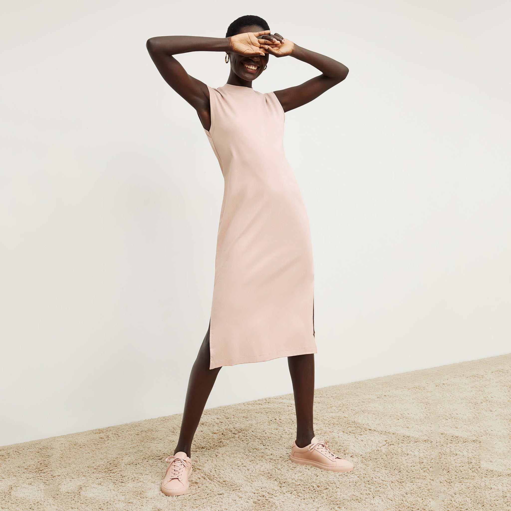 Front image of a woman standing wearing the Lou Dress—Compact Cotton in Dusty Pink