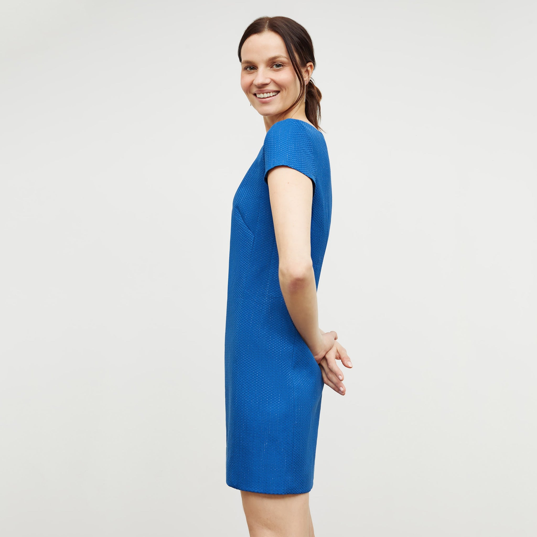 Side image of a woman standing wearing the marie dress in basketweave jacquard in azure