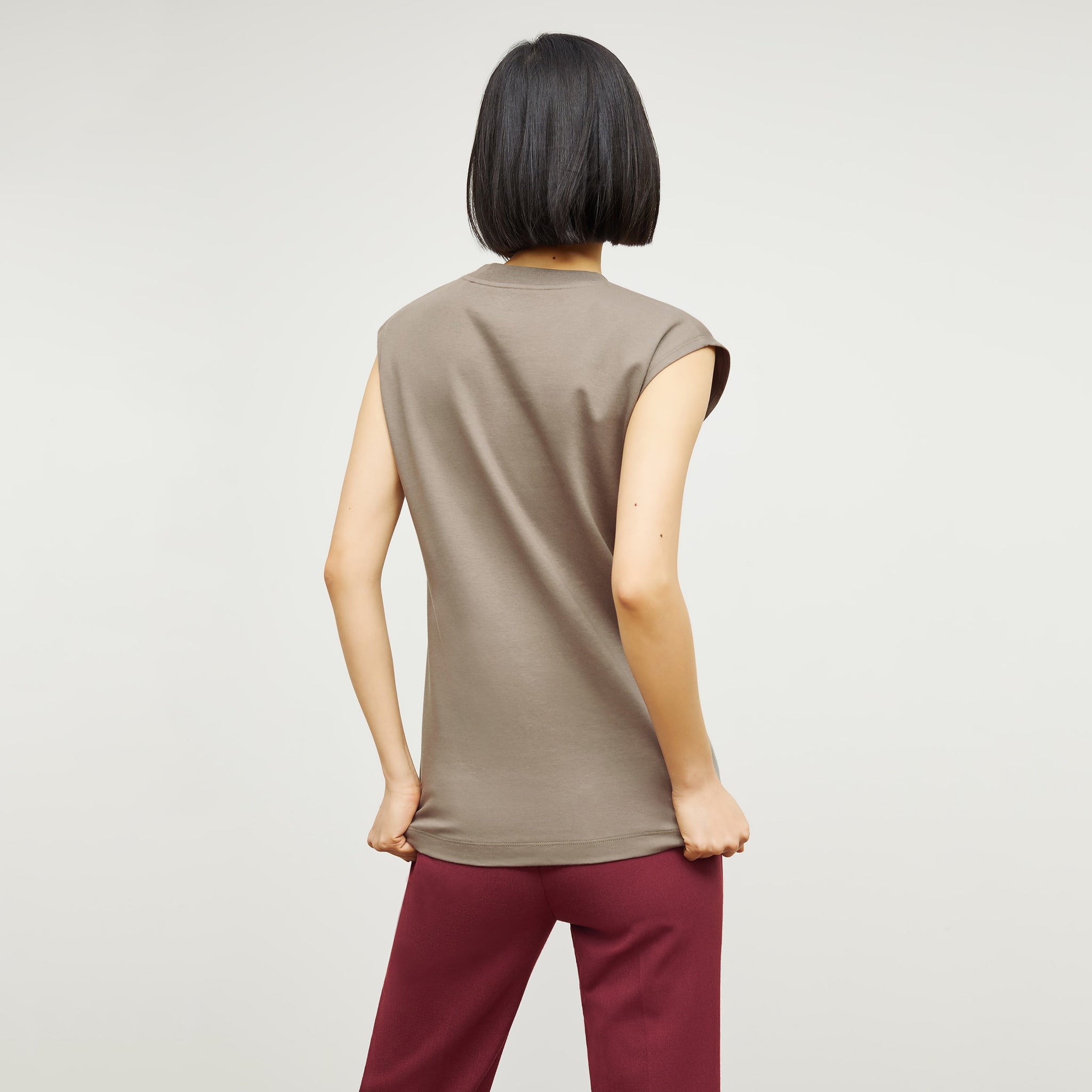 Back image of a woman standing wearing the Alina T-Shirt—Compact Cotton in Pebble