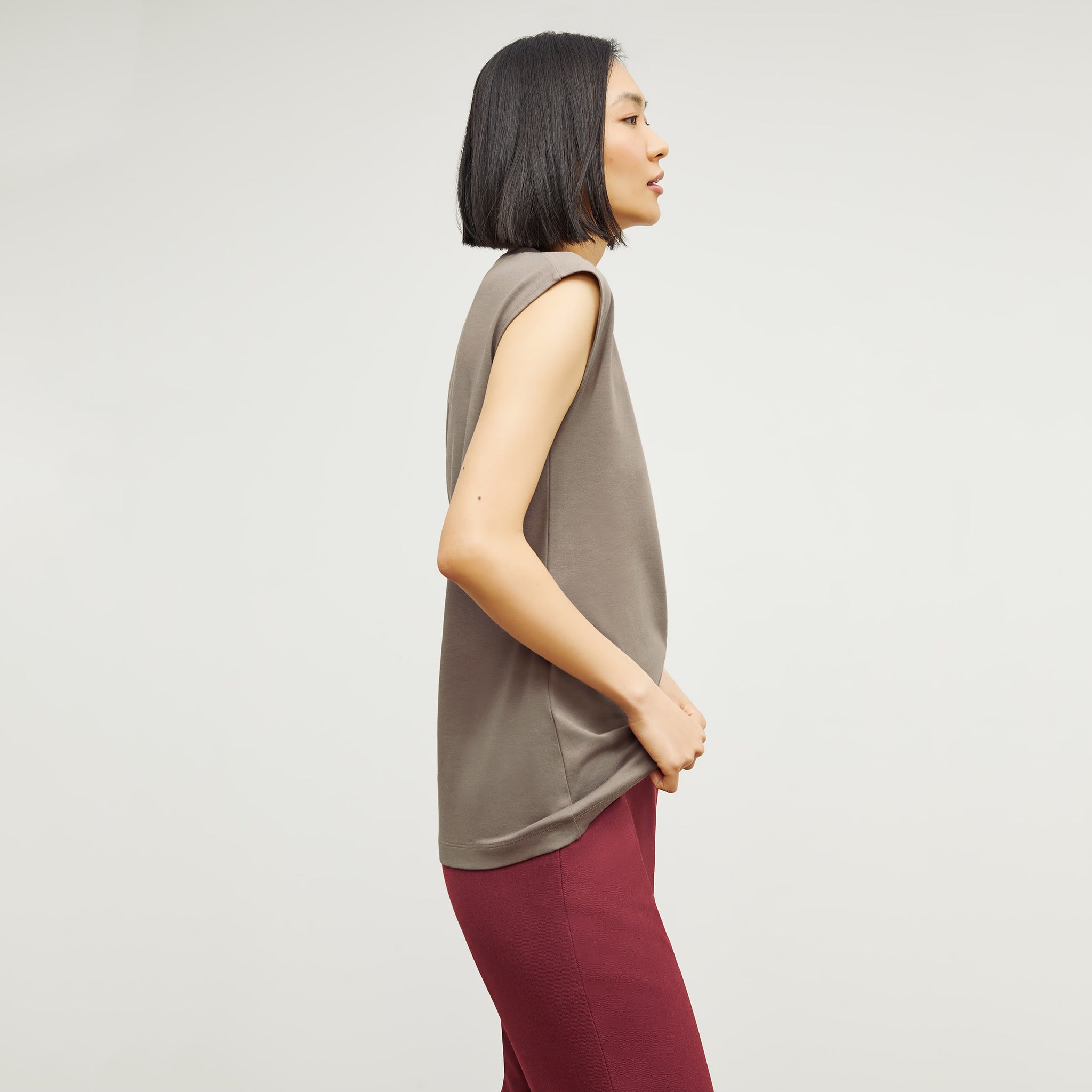 Side image of a woman standing wearing the Alina T-Shirt—Compact Cotton in Pebble