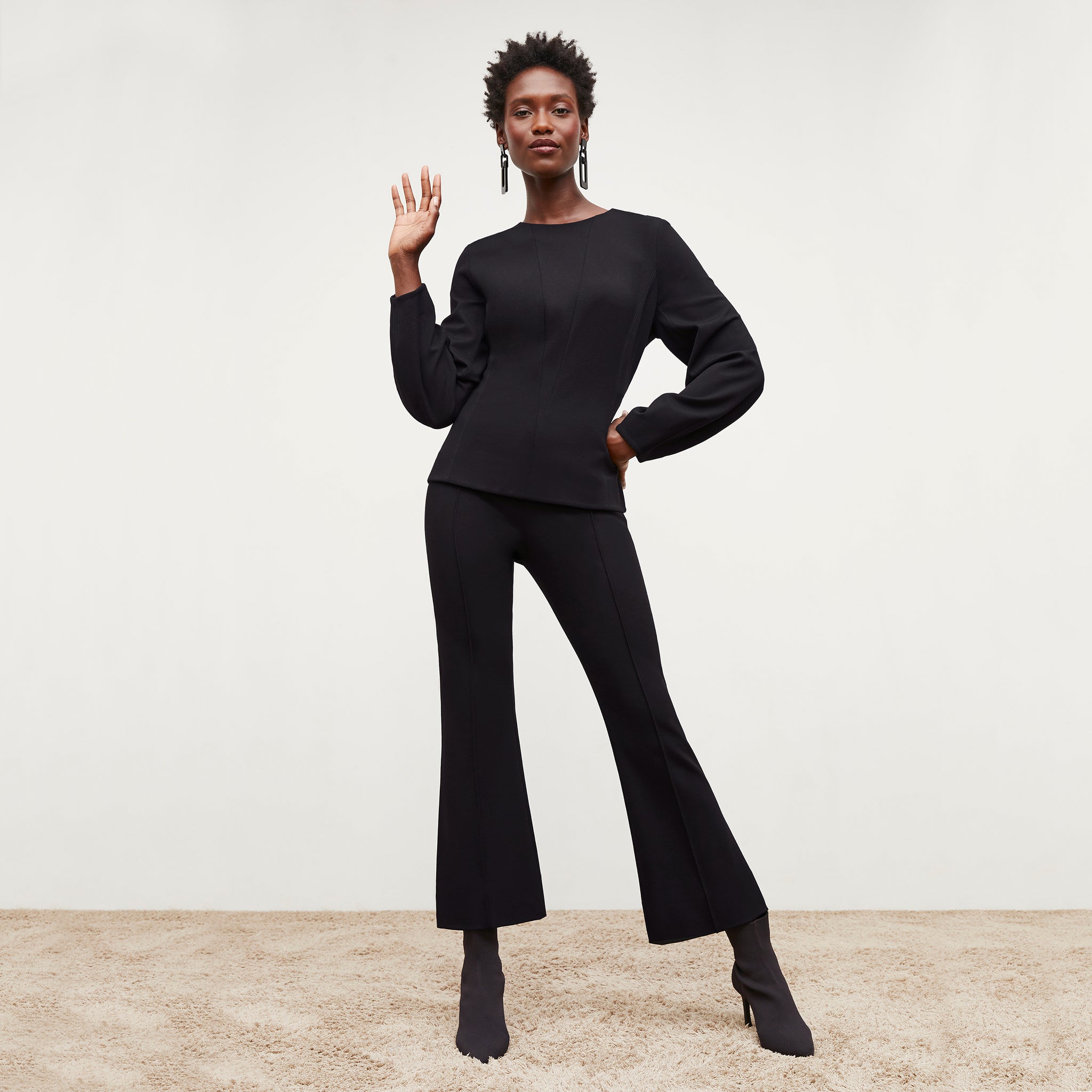 Front image of a woman standing wearing the rashida top in black 