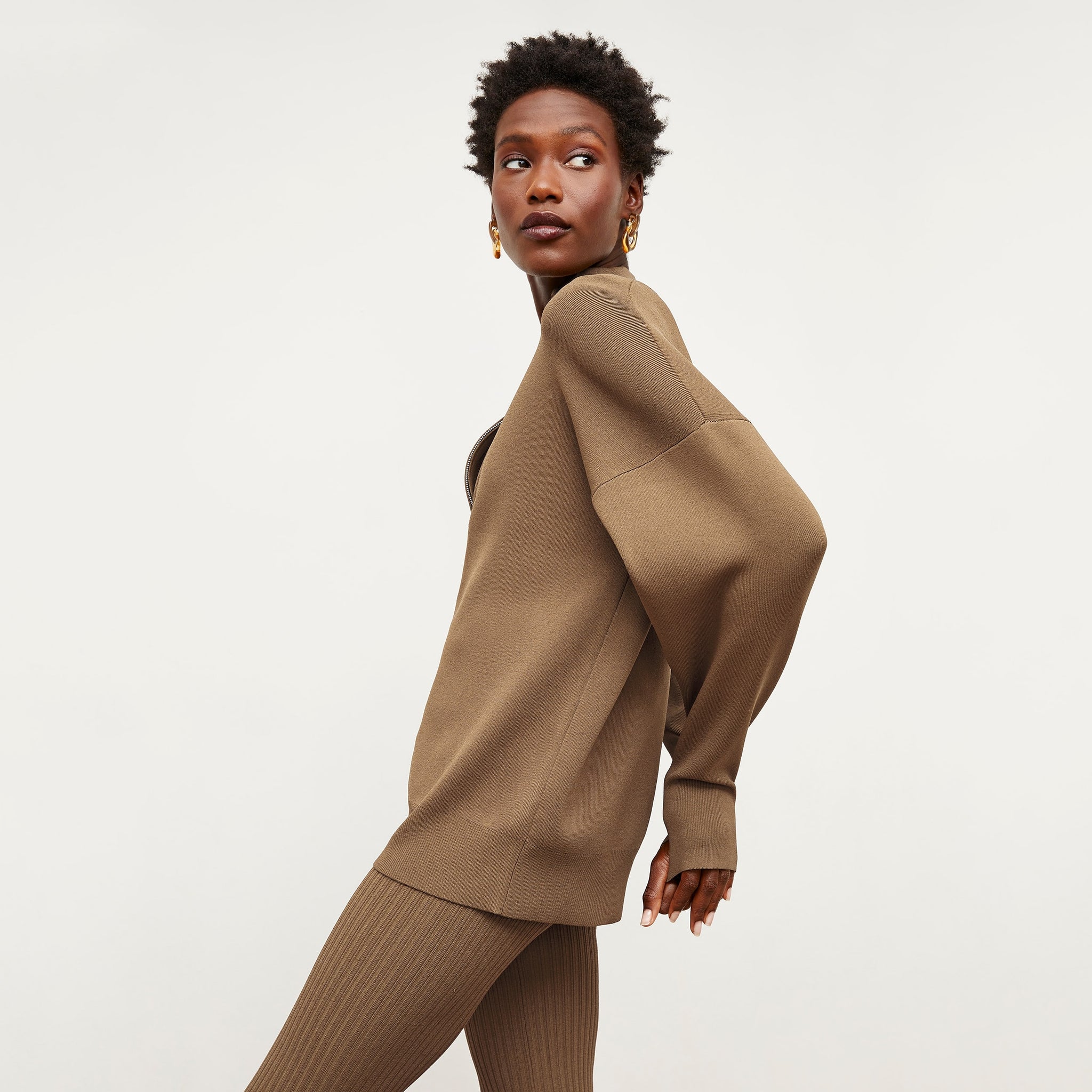 Side image of a woman standing wearing the Athens Half Zip—Jardigan Knit in Light Bronze