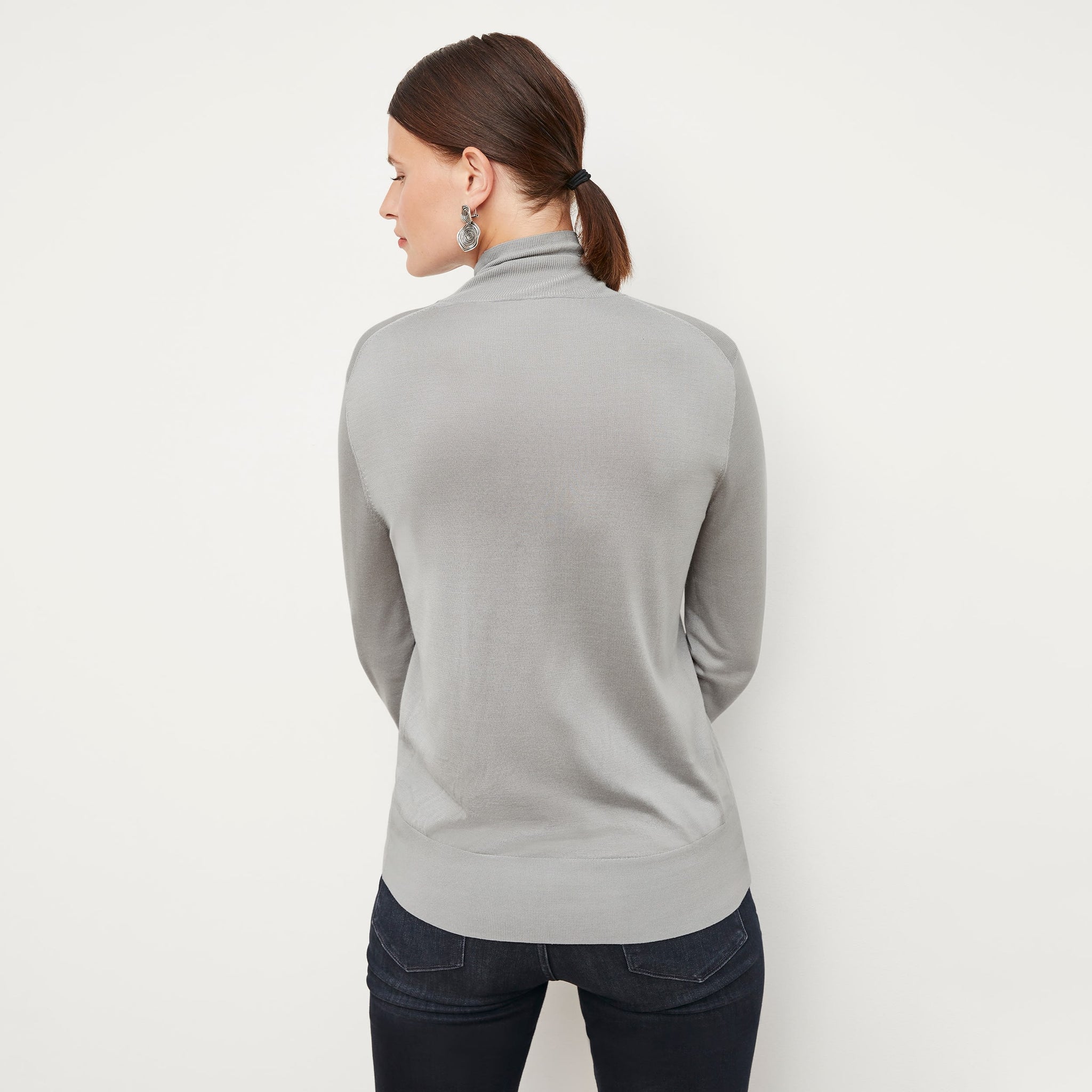 Back image of a woman standing wearing the elizabeth top in silk jersey in pale gray