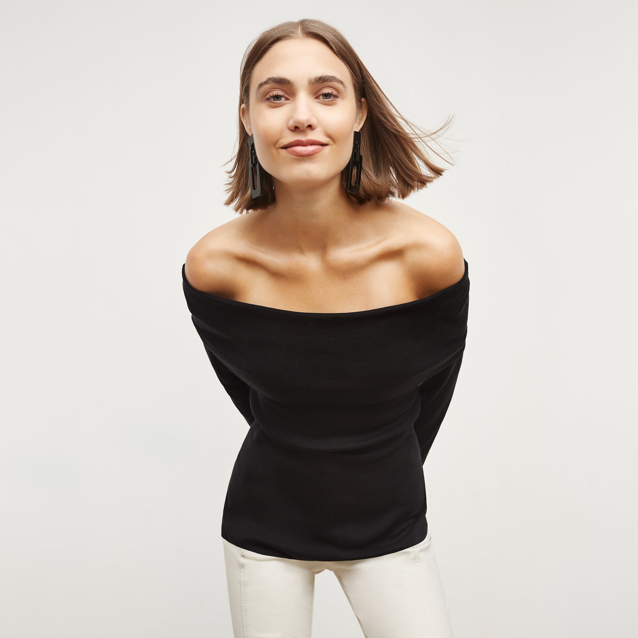 Front image of a woman standing wearing the dae top in silk jersey in black