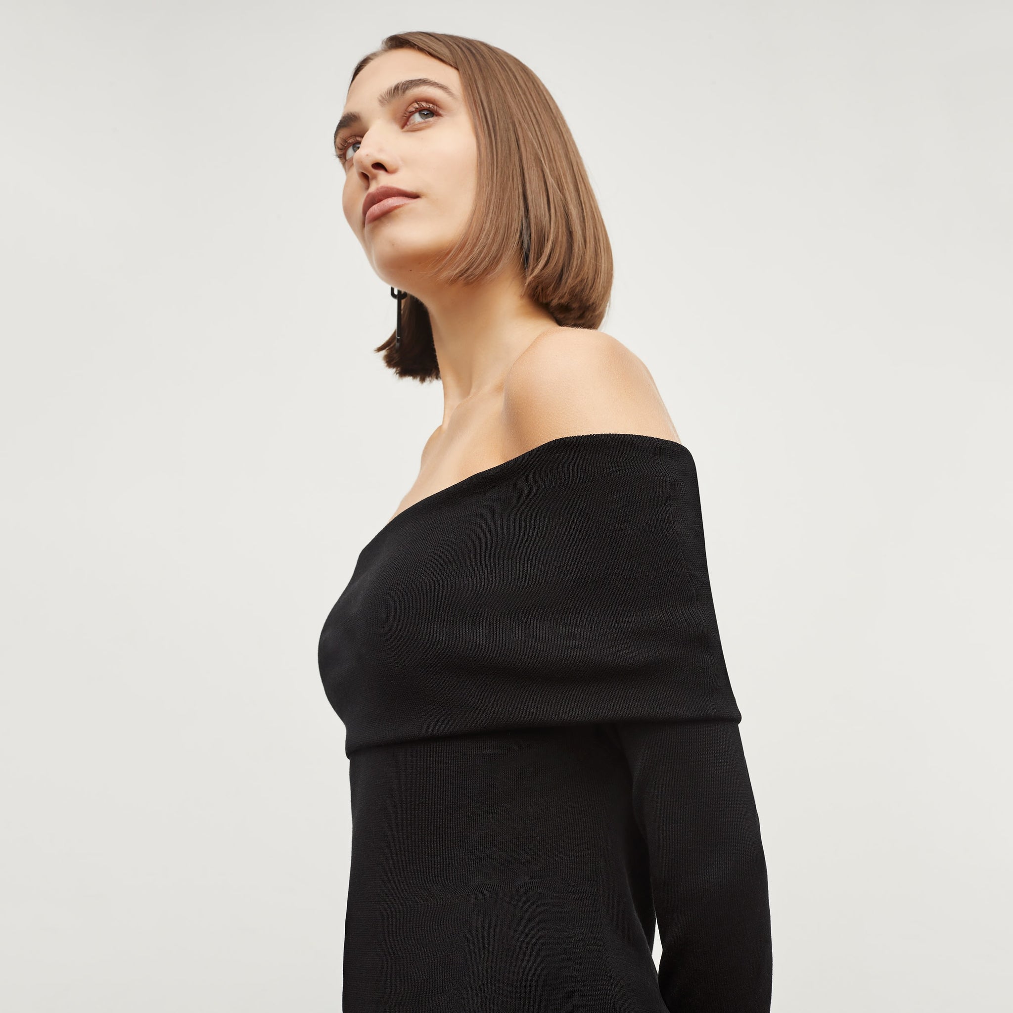 Side image of a woman standing wearing the dae top in silk jersey in black