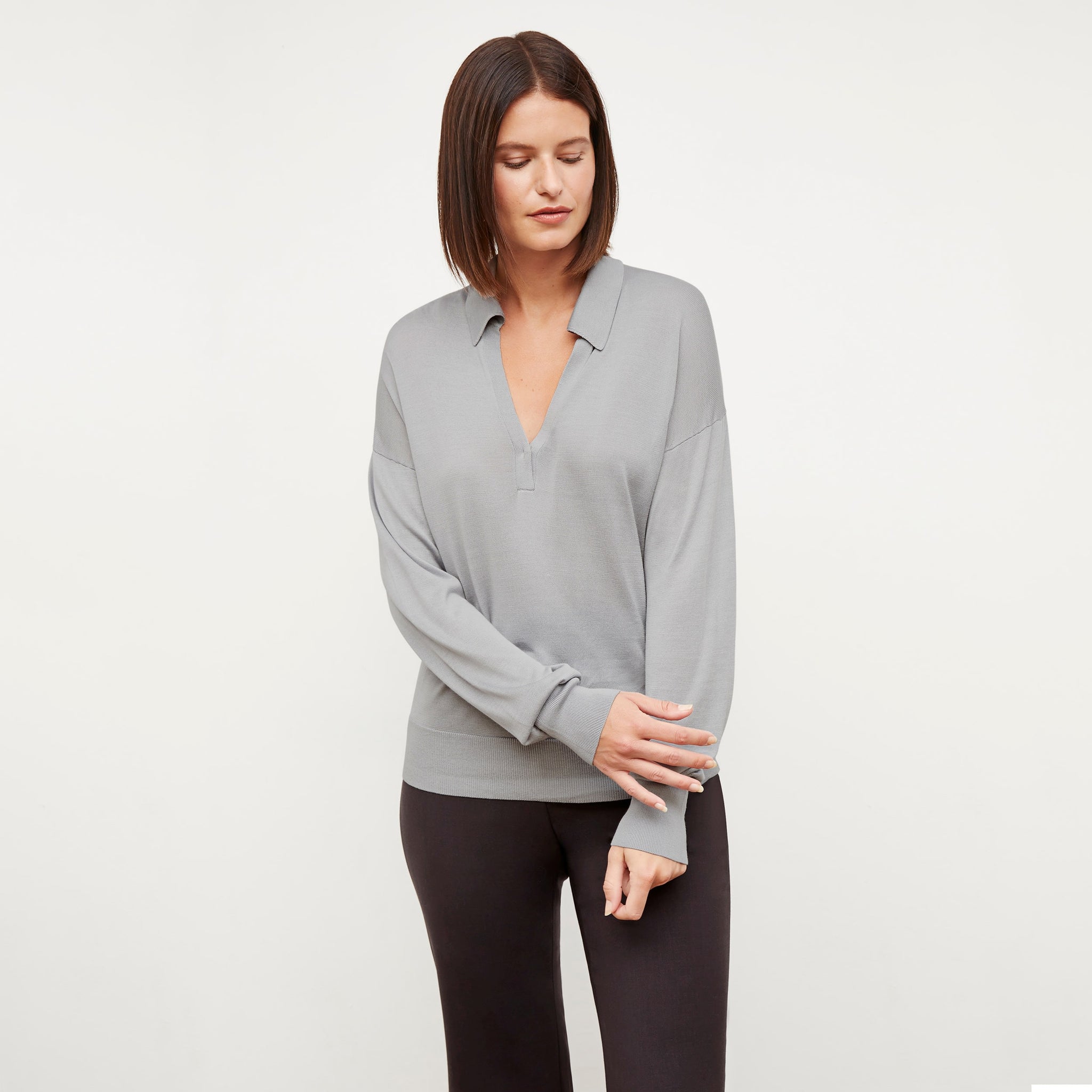 Front image of a woman standing wearing the leo top in silk jersey in pale gray