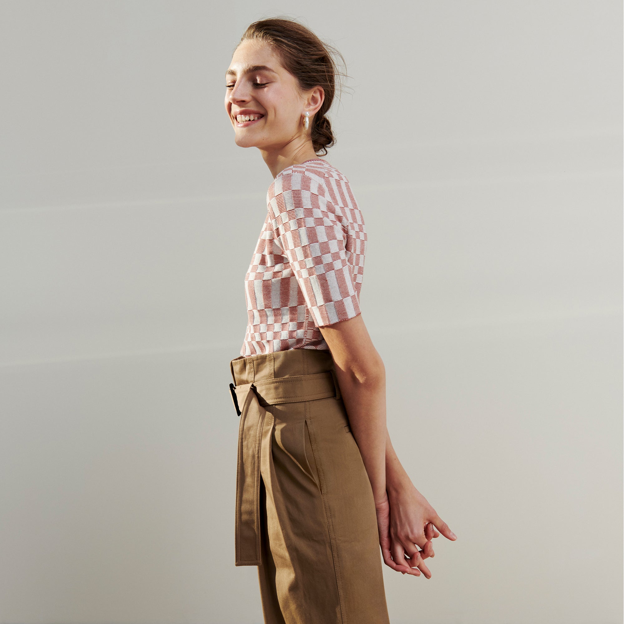 Side image of a woman wearing the Charli Top - Checkered Knit in Red Clay / Natural