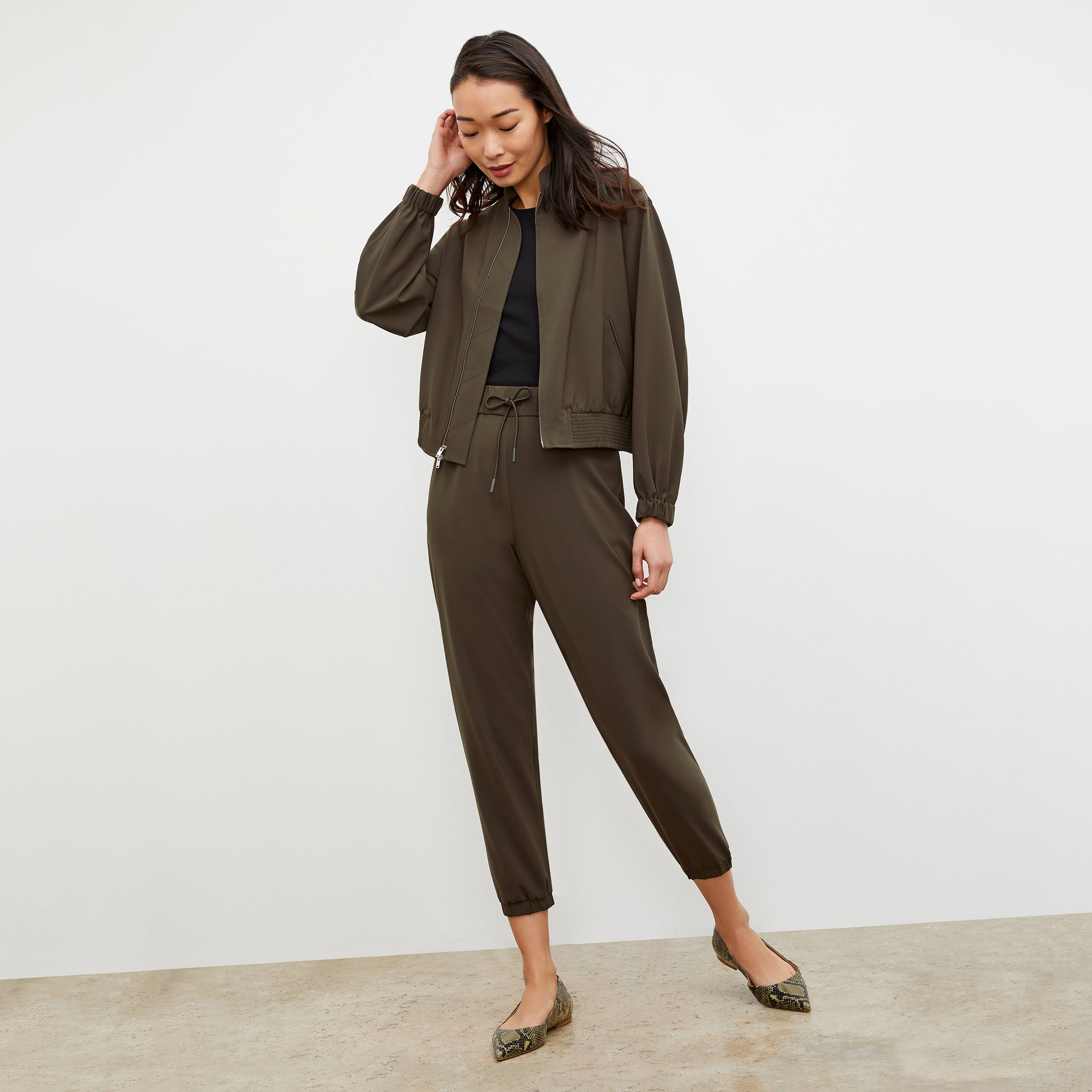 Back image of a woman standing wearing the Delaney Jogger—OrigamiTech in Olive 