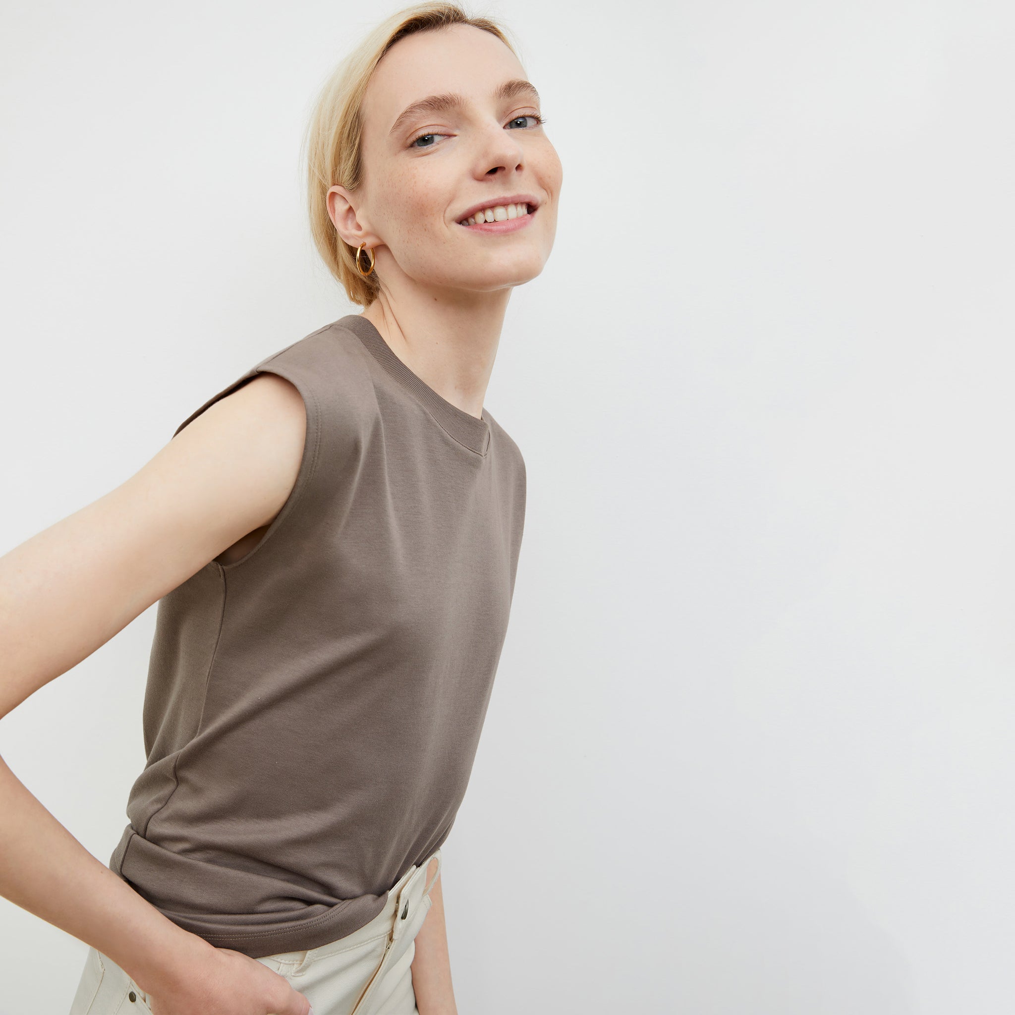 Side image of a woman standing wearing the Alina T-Shirt—Compact Cotton in Pebble 