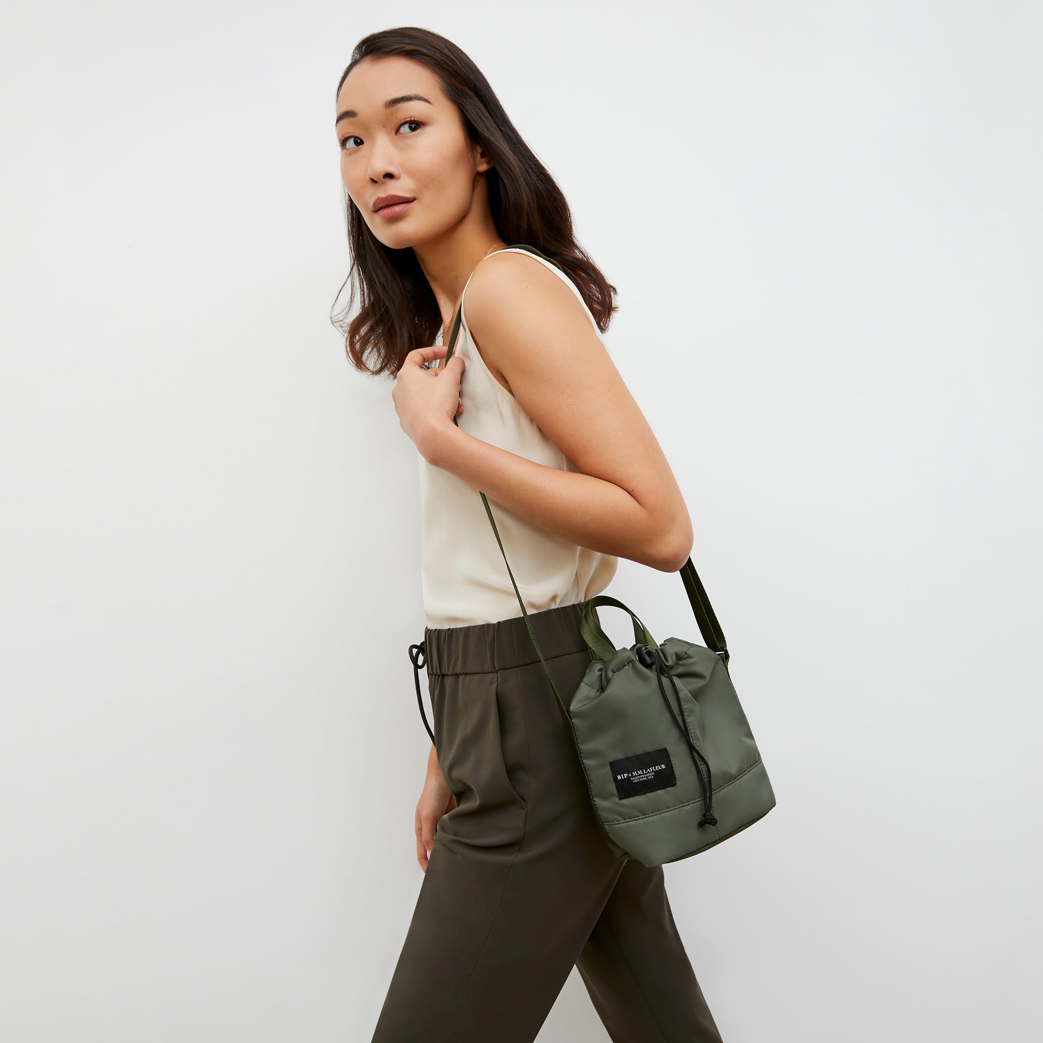 Front image of a woman wearing the Bags in Progress x MM Padded Mini Bucket Bag in Khaki Green