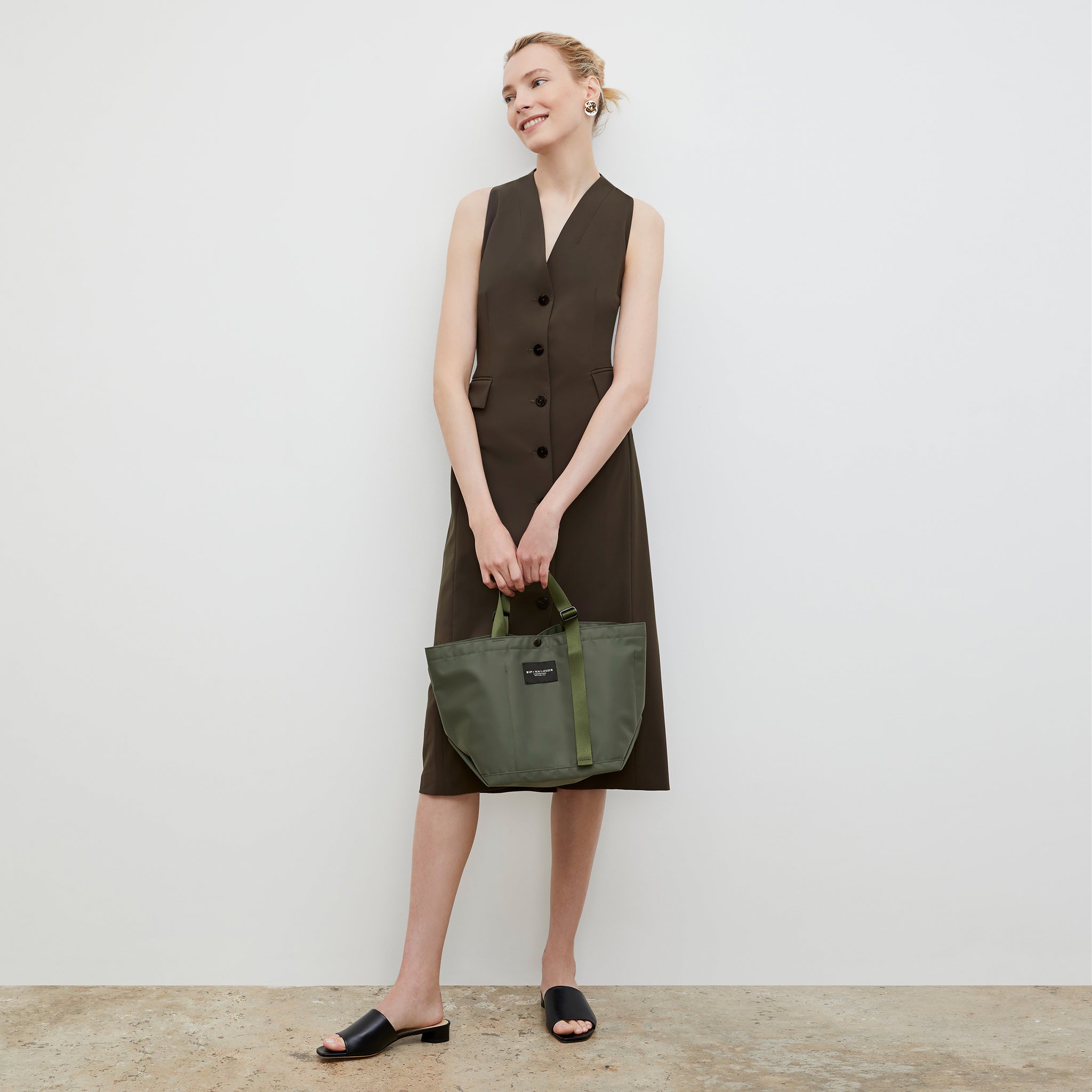 Front image of a woman wearing the Bags in Progress x MM Small Carry All Tote  in Khaki Green