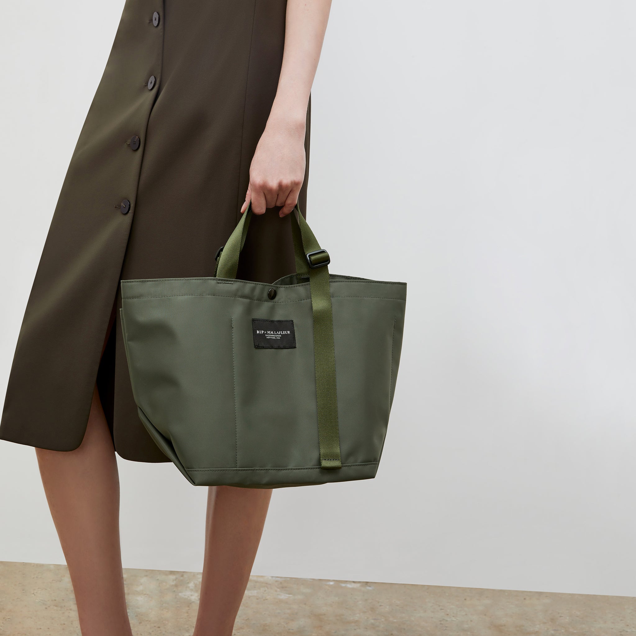 Front image of a woman wearing the Bags in Progress x MM Small Carry All Tote  in Khaki Green