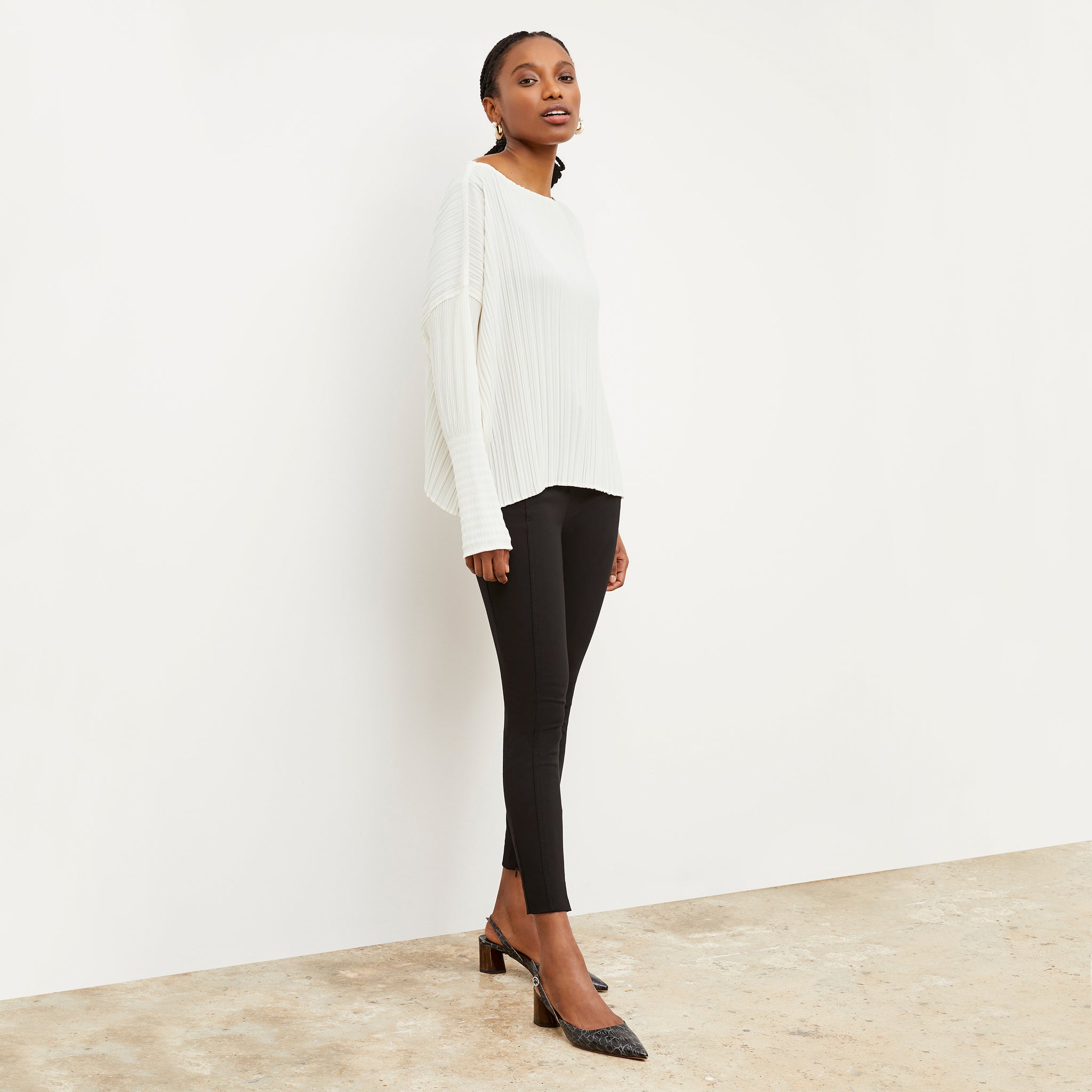 Side image of a woman wearing the Lasha Top - Micro Pleat in Ivory