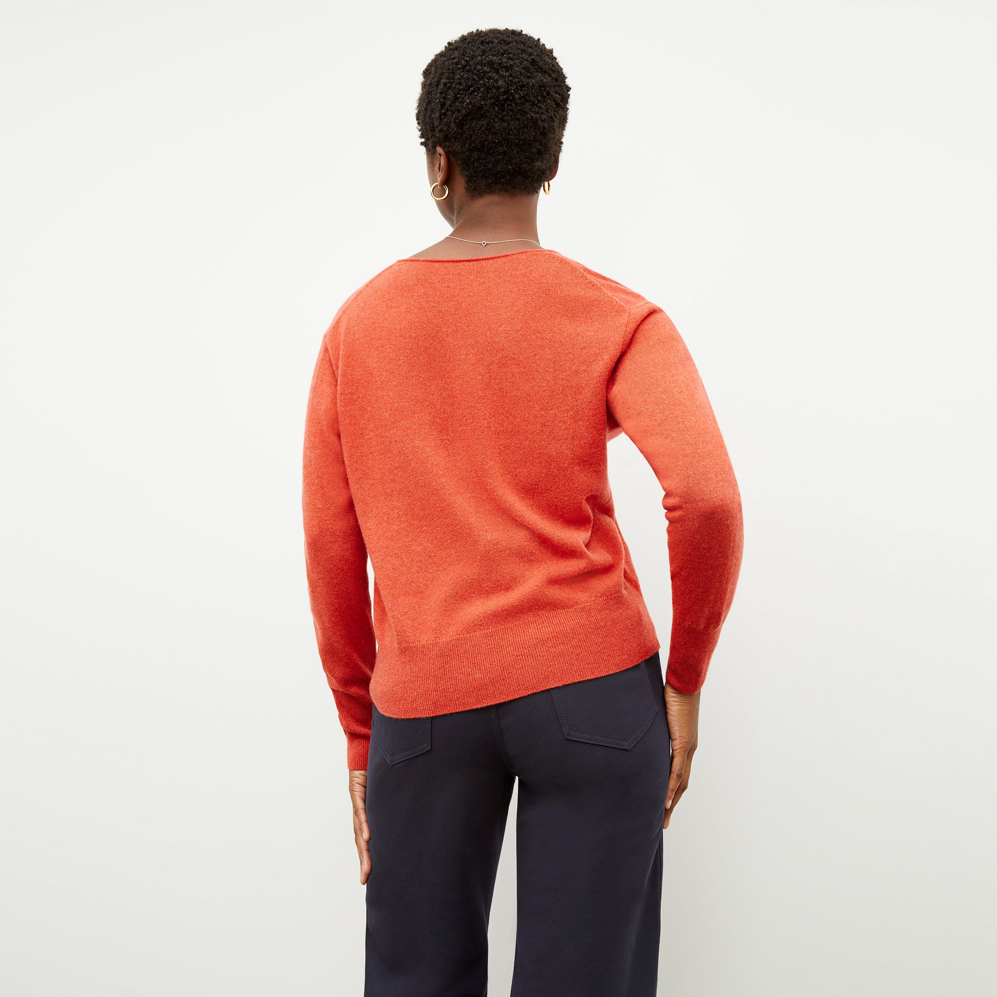 Back image of a woman wearing the martha sweater in papaya